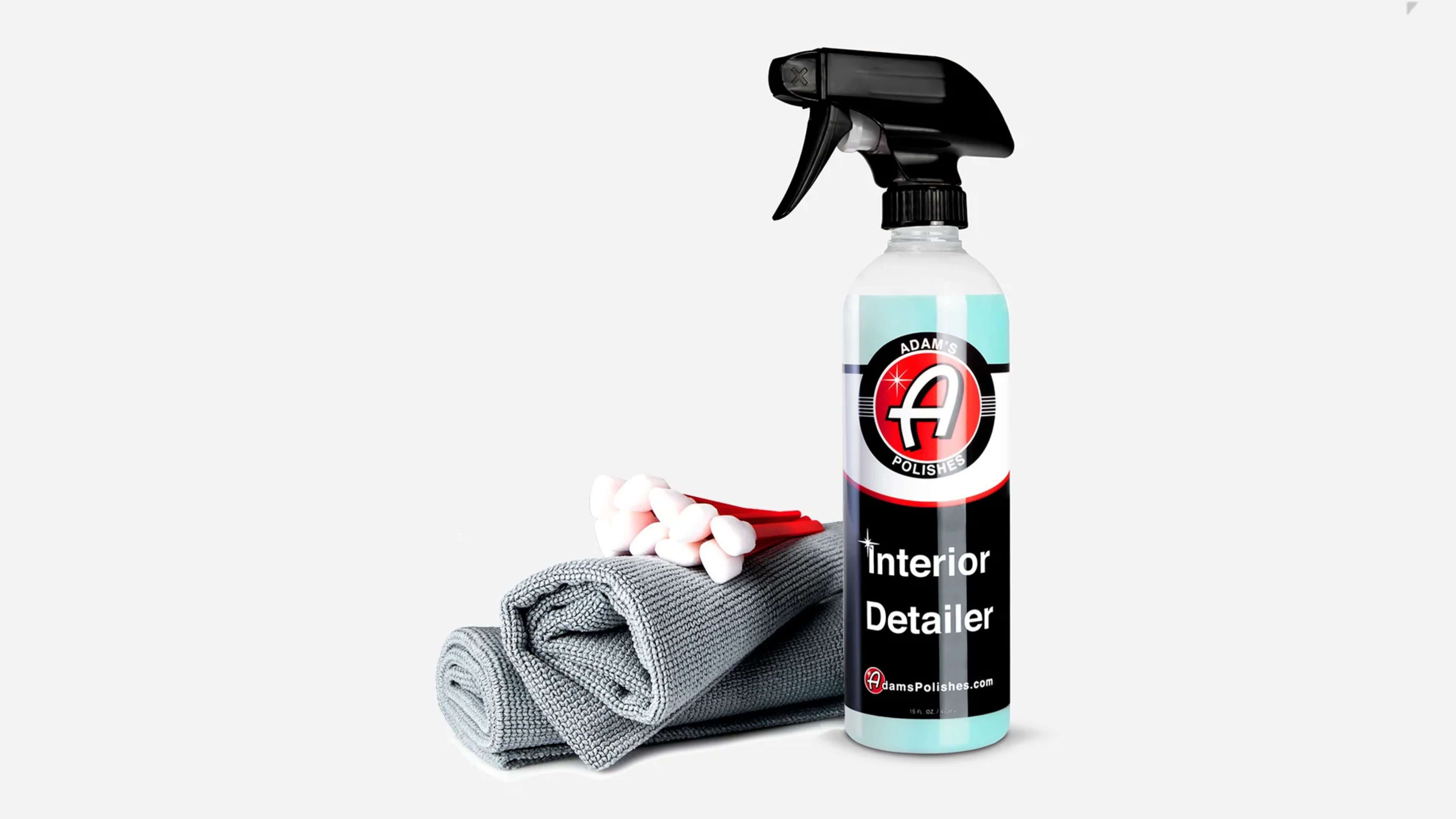 A bottle of Adam's Polishes Interior Detailer with microfiber cloth and cotton swabs, perfect for cleaning car upholstery.