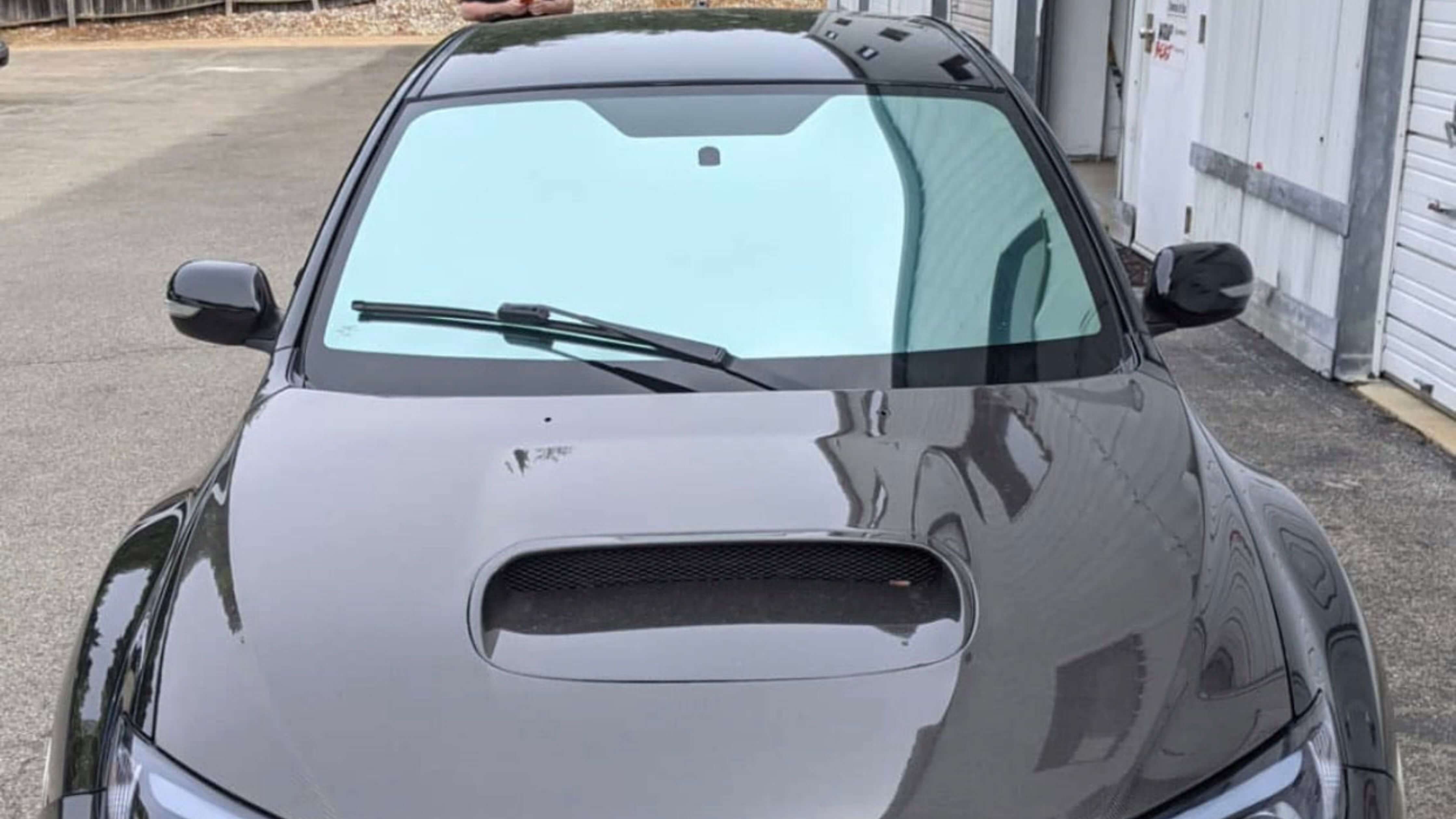 A car with 20 tint parked in front of garage doors, showcasing tinted windows.
