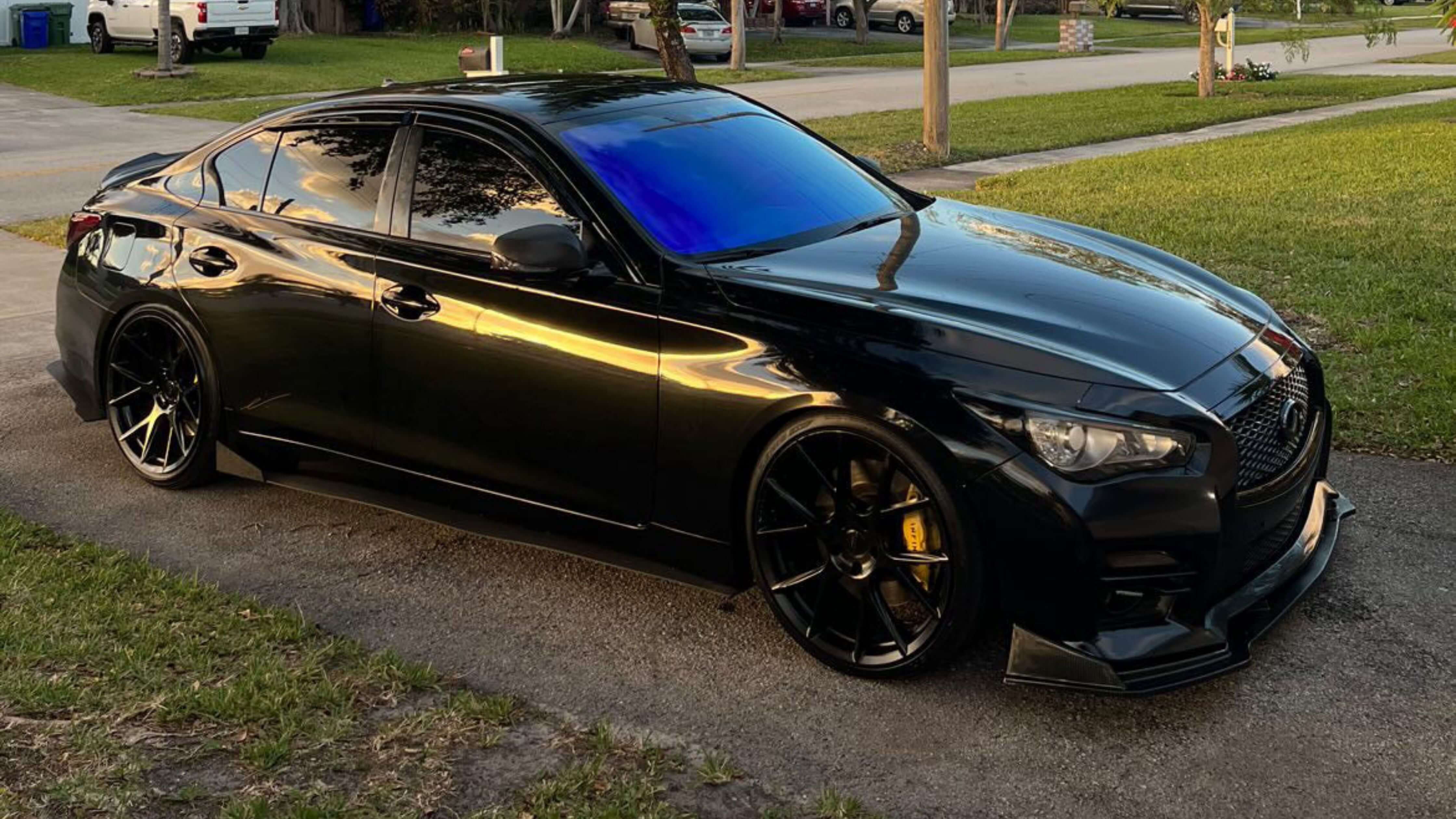 A sleek black car with tinted windows parked on a driveway, showcasing the stylish and functional aspects of window tinting for leased vehicles.