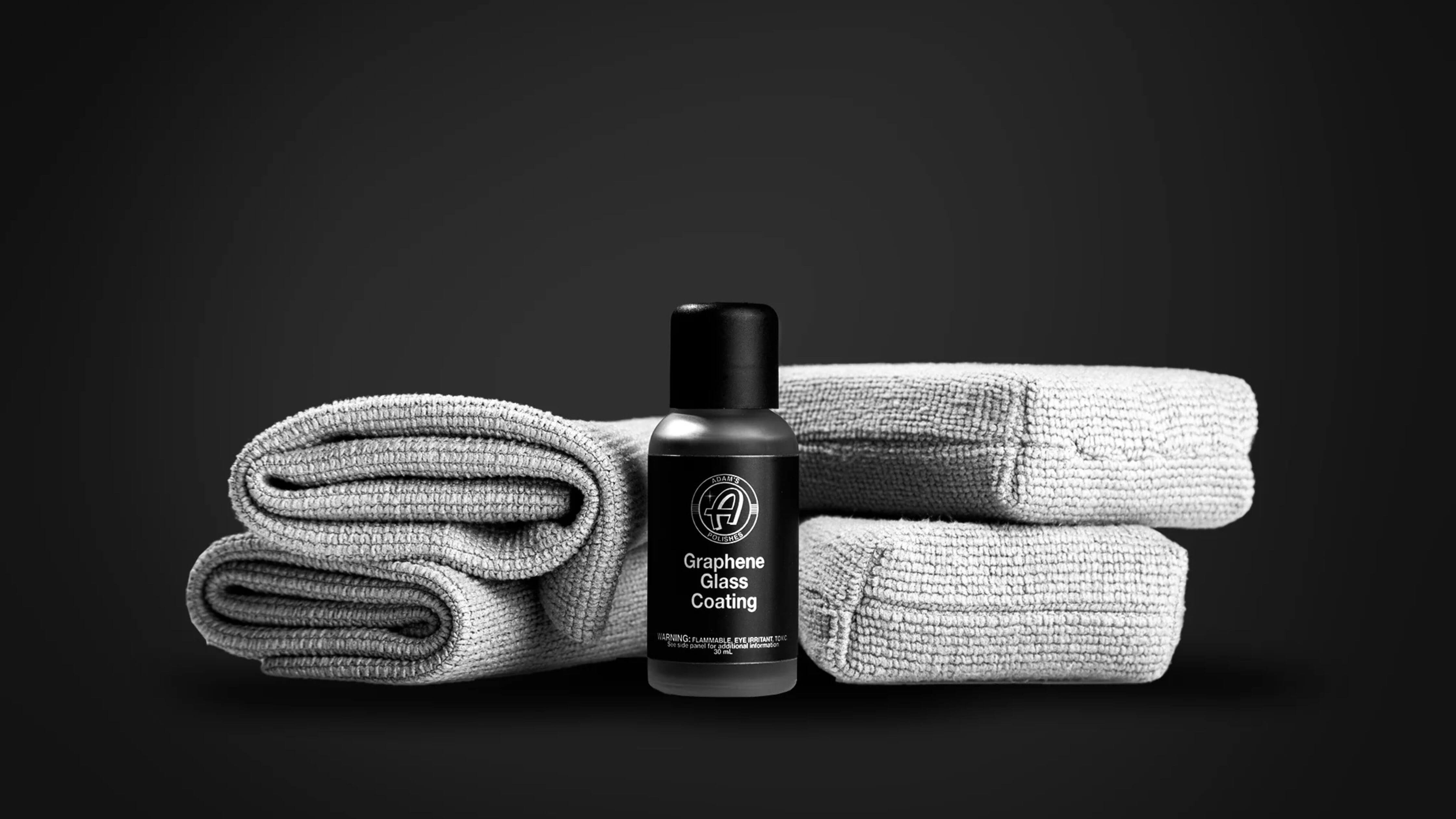 Car detailing kit essentials displayed: Graphene Glass Coating with gray towels.