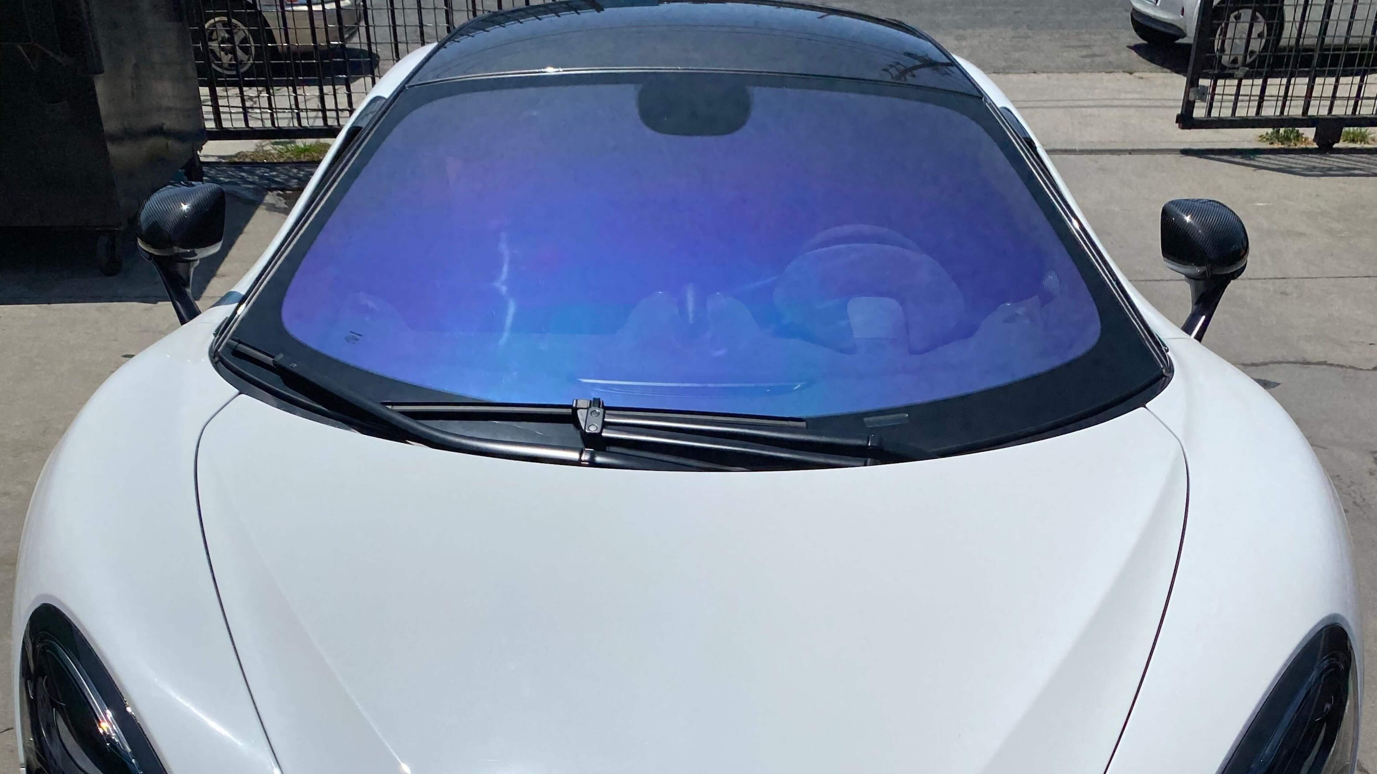 White sports car with blue-tinted windshield parked on street.