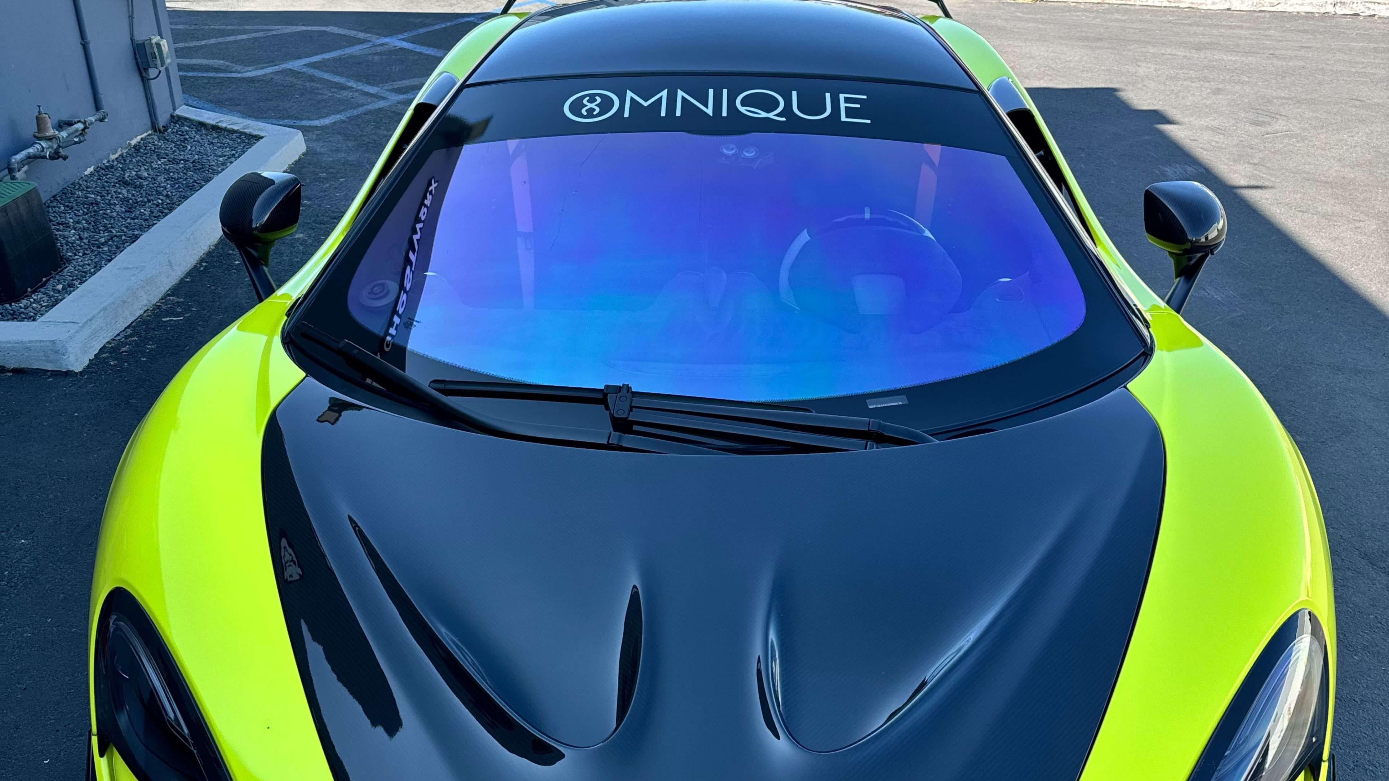 Green sports car with black hood and clear windows, illustrating how to remove tint from car window.