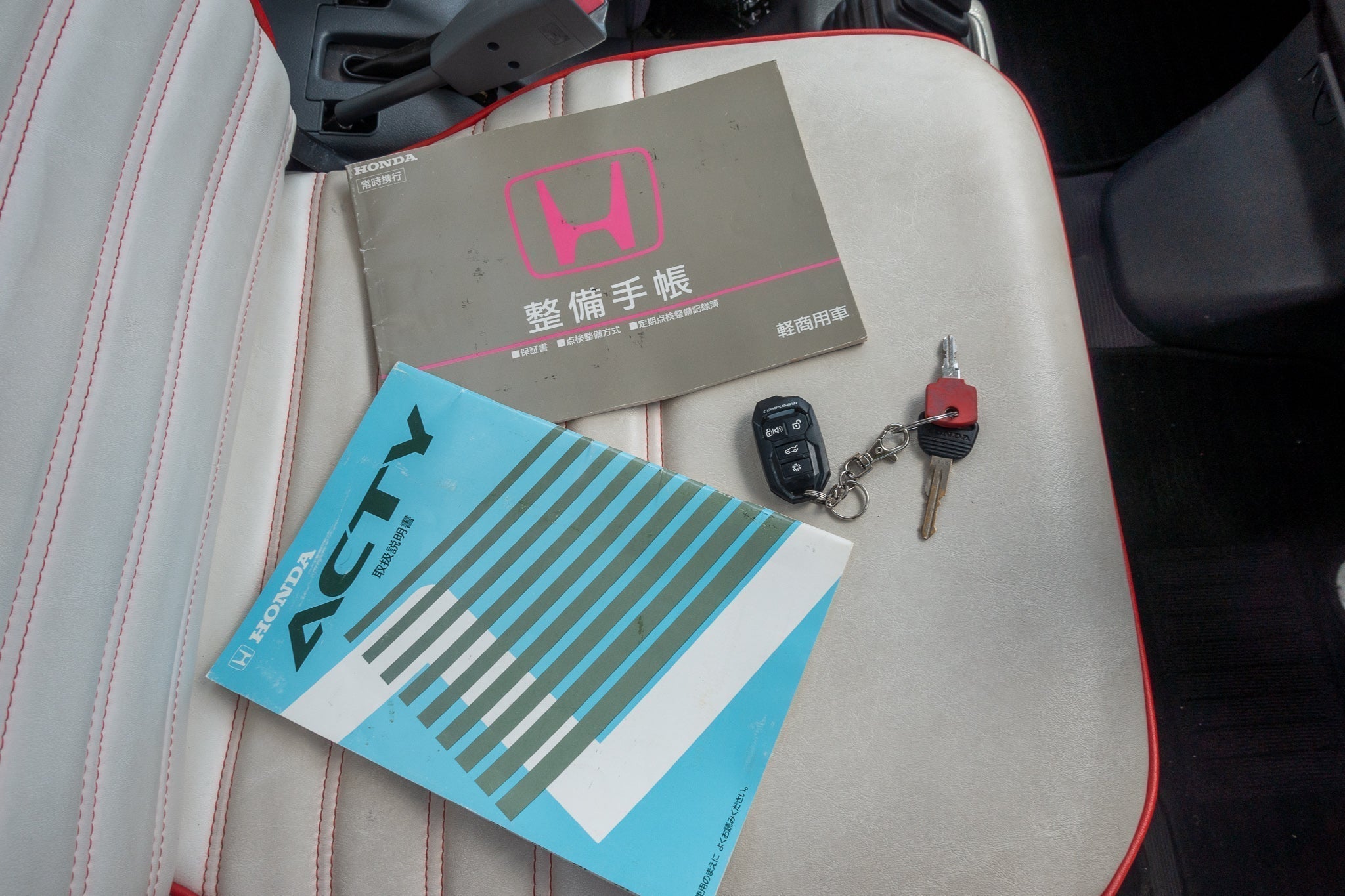 Honda JDM factory manuals sitting on top of a kei truck driver’s seat