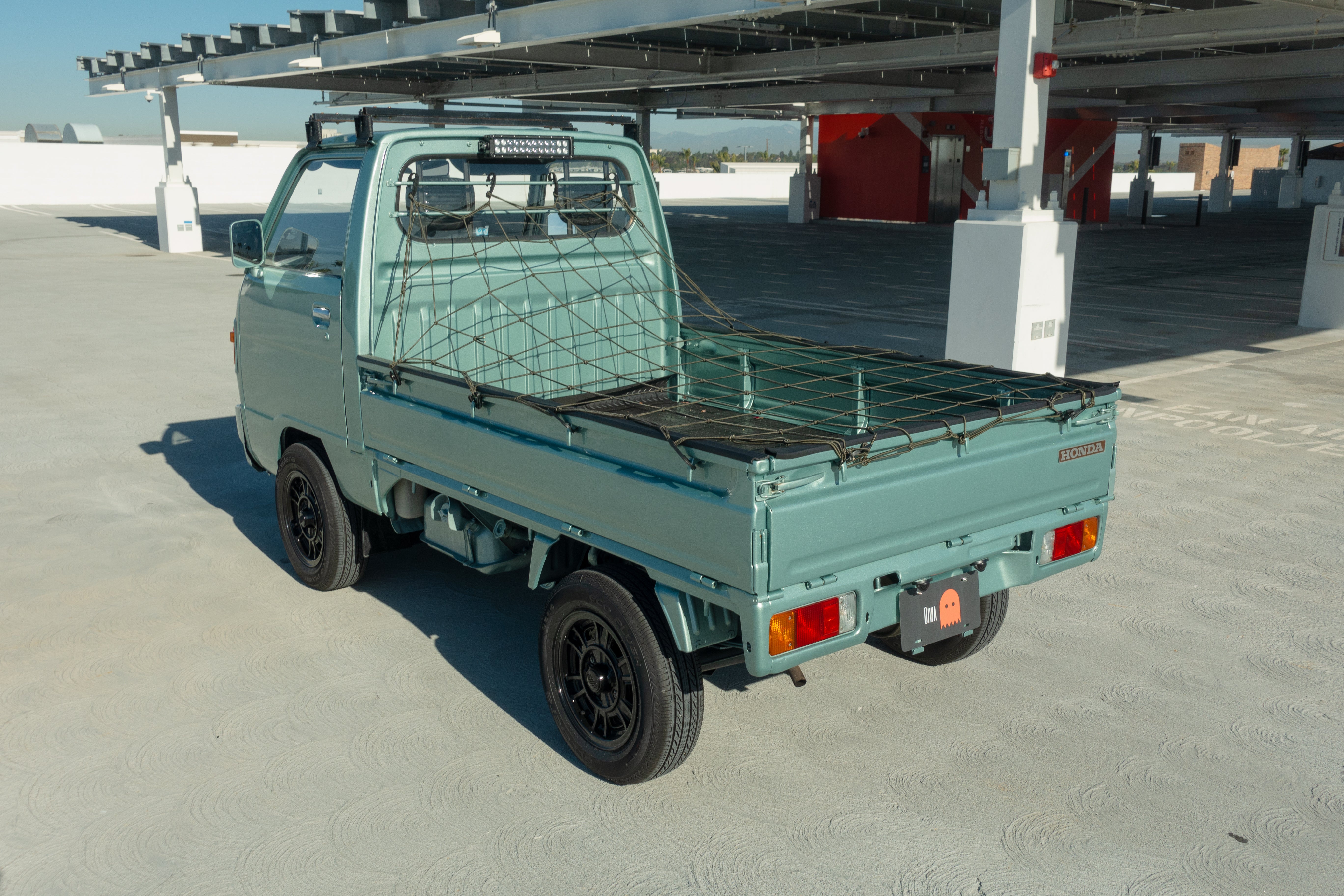 A Japanese Kei Truck on the road with an overlay of top insurance provider logos, showcasing the importance of proper coverage.