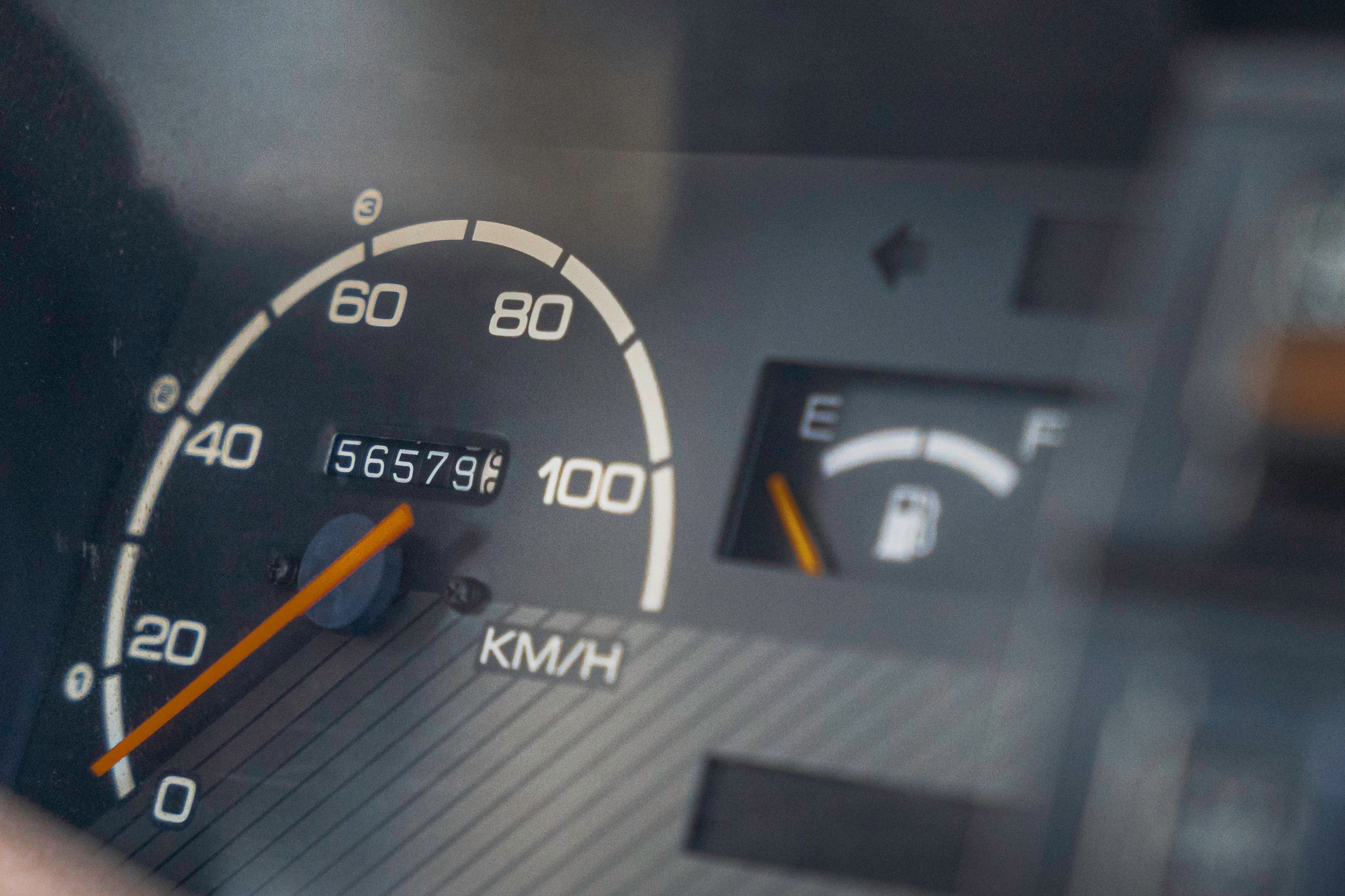 Close-up of a car dashboard showing a speedometer reading 0 km/h, an odometer at 56579, and a fuel gauge indicating low fuel.