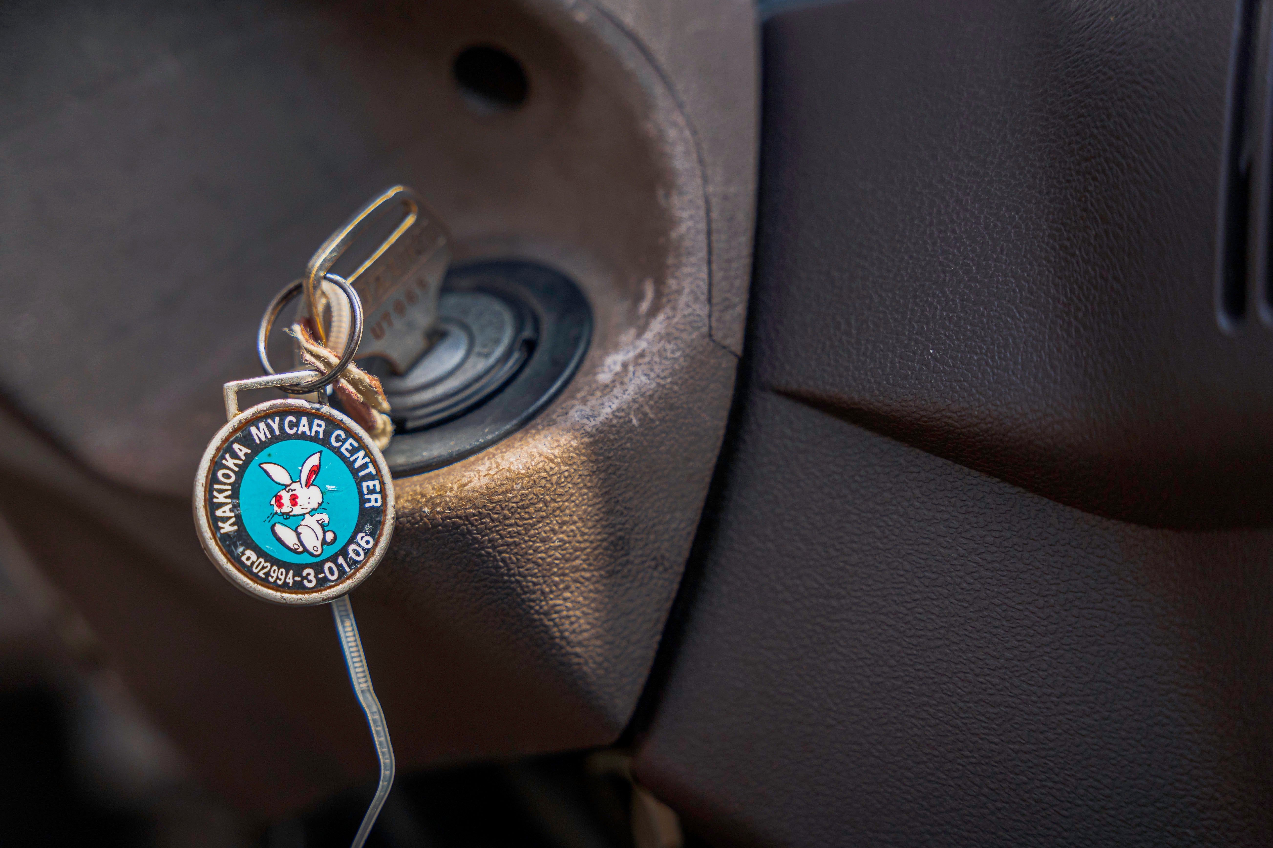 A car key with a "Kakioka My Car Center" keychain is inserted into an ignition.