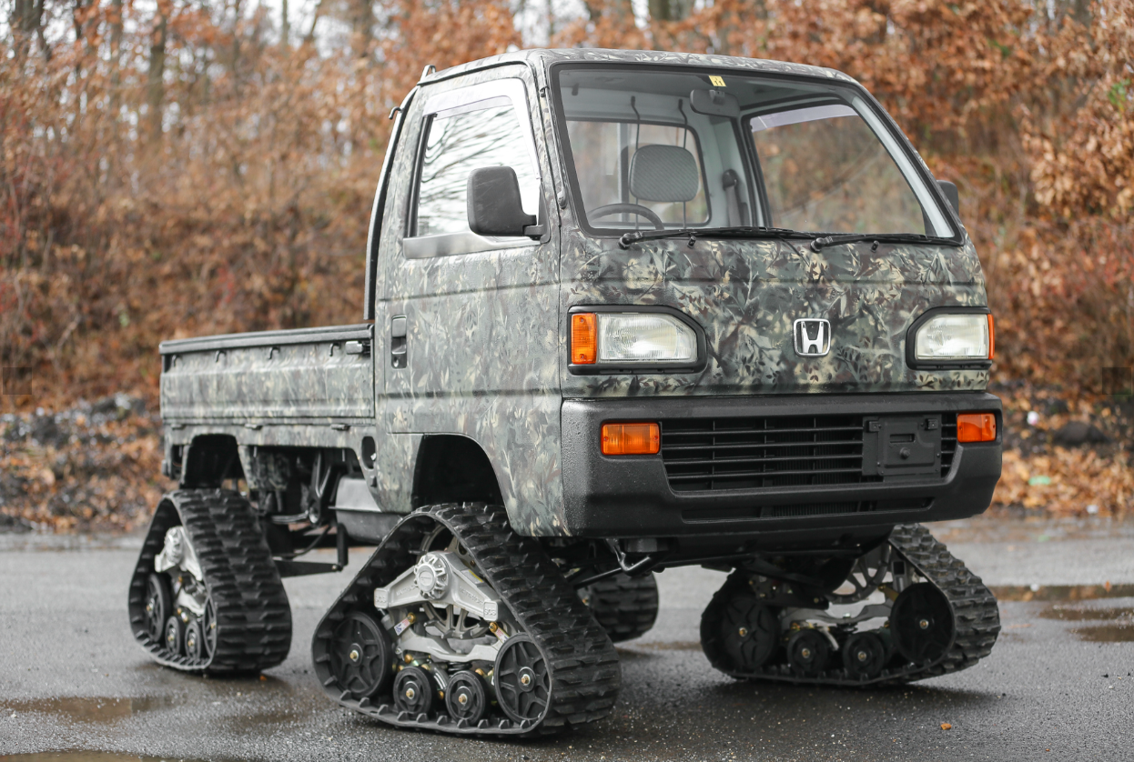 Customized Honda Acty with rugged camouflage wrap and tank-style tracks, perfect for conquering extreme off-road terrain.
