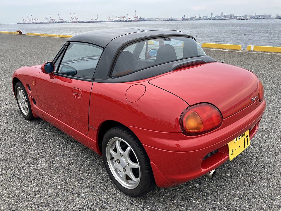A sporty red kei car shown parked at a California port