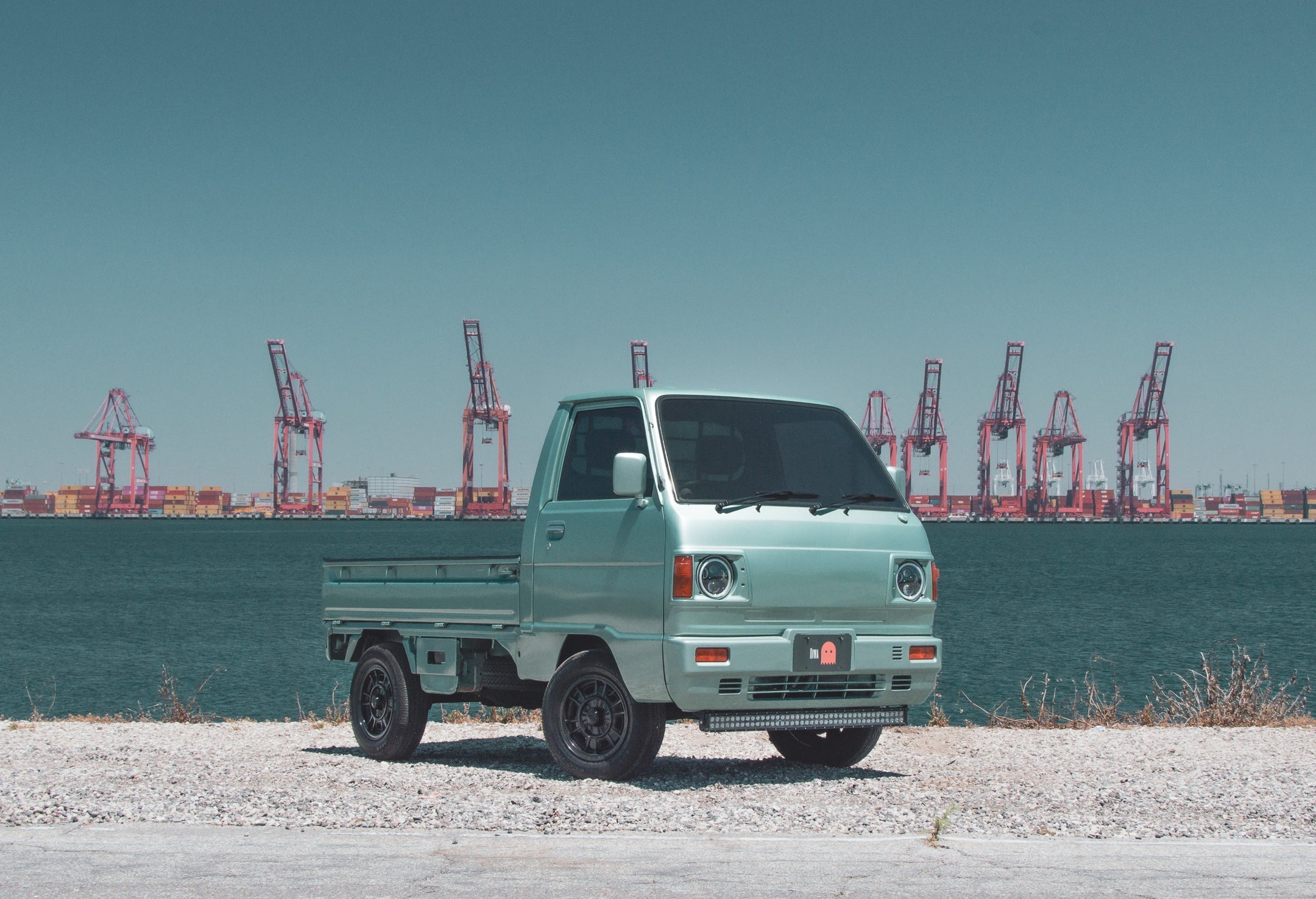 Pandem Suzuki Carry with wide-body kit on scenic road, highlighting transformation and compact design.