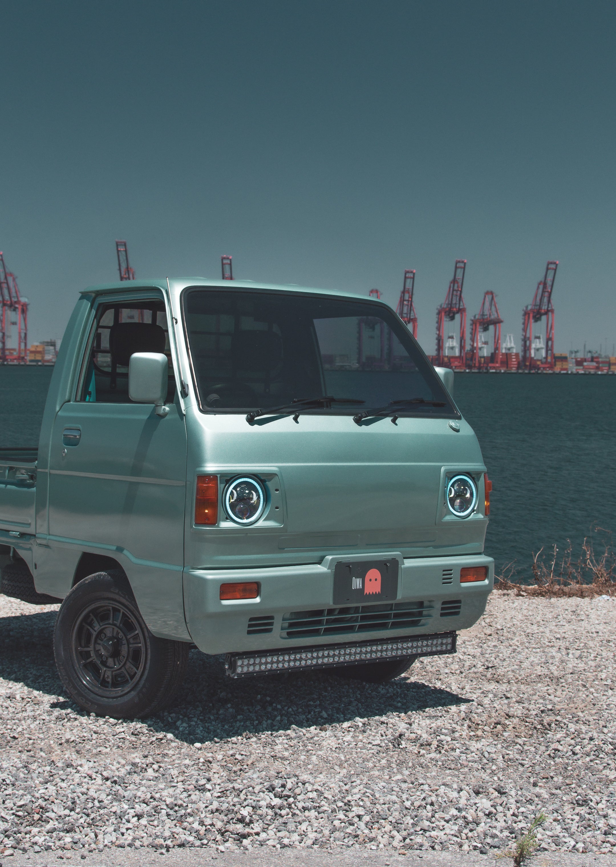 Suzuki Carry Truck parked in urban setting, showcasing compact design and utility.