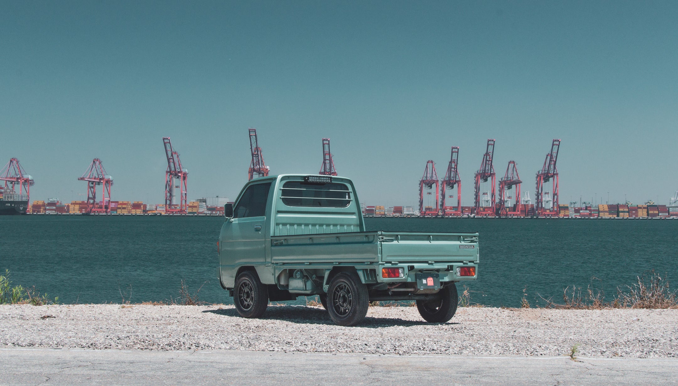 Daihatsu Kei Truck parked with a scenic countryside background, showcasing its compact design and efficiency.