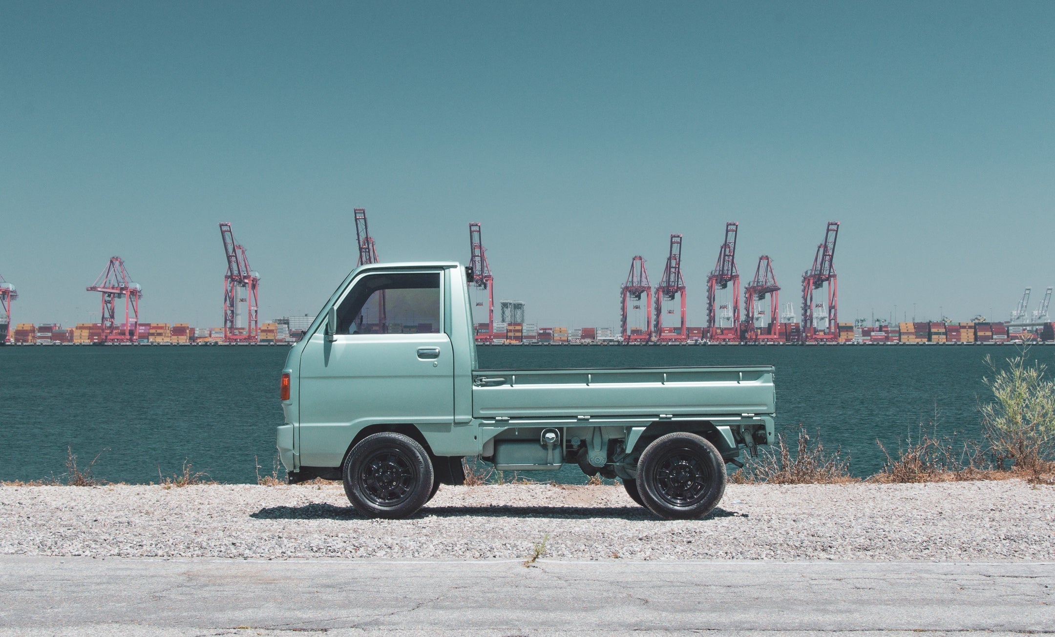 1989 Suzuki Carry micro-truck on rural road, highlighting compact efficiency and timeless design.