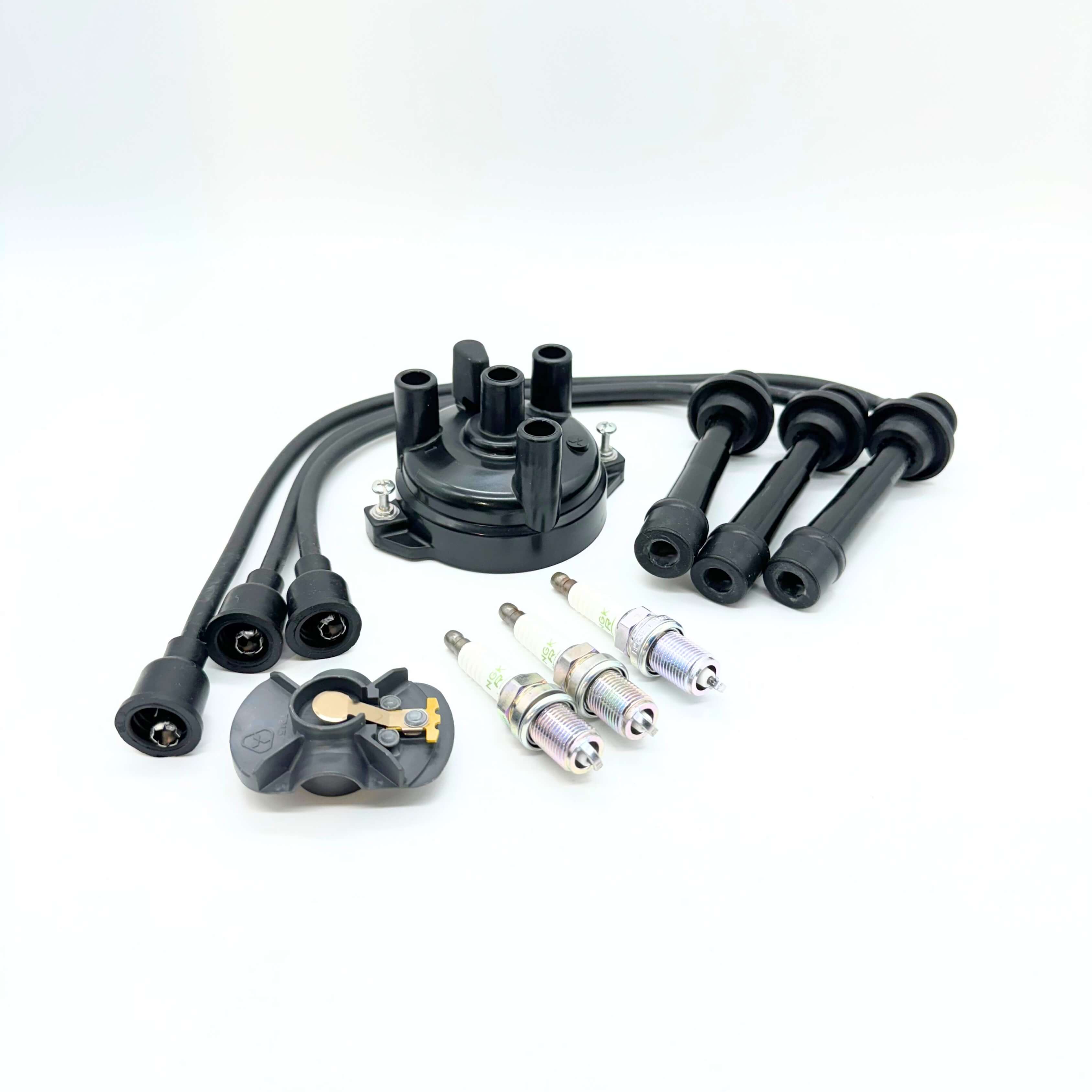 Suzuki Carry ignition repair kit with distributor cap, ignition cables, rotor, and spark plugs laid out on a white background, suitable for engine maintenance and performance optimization.