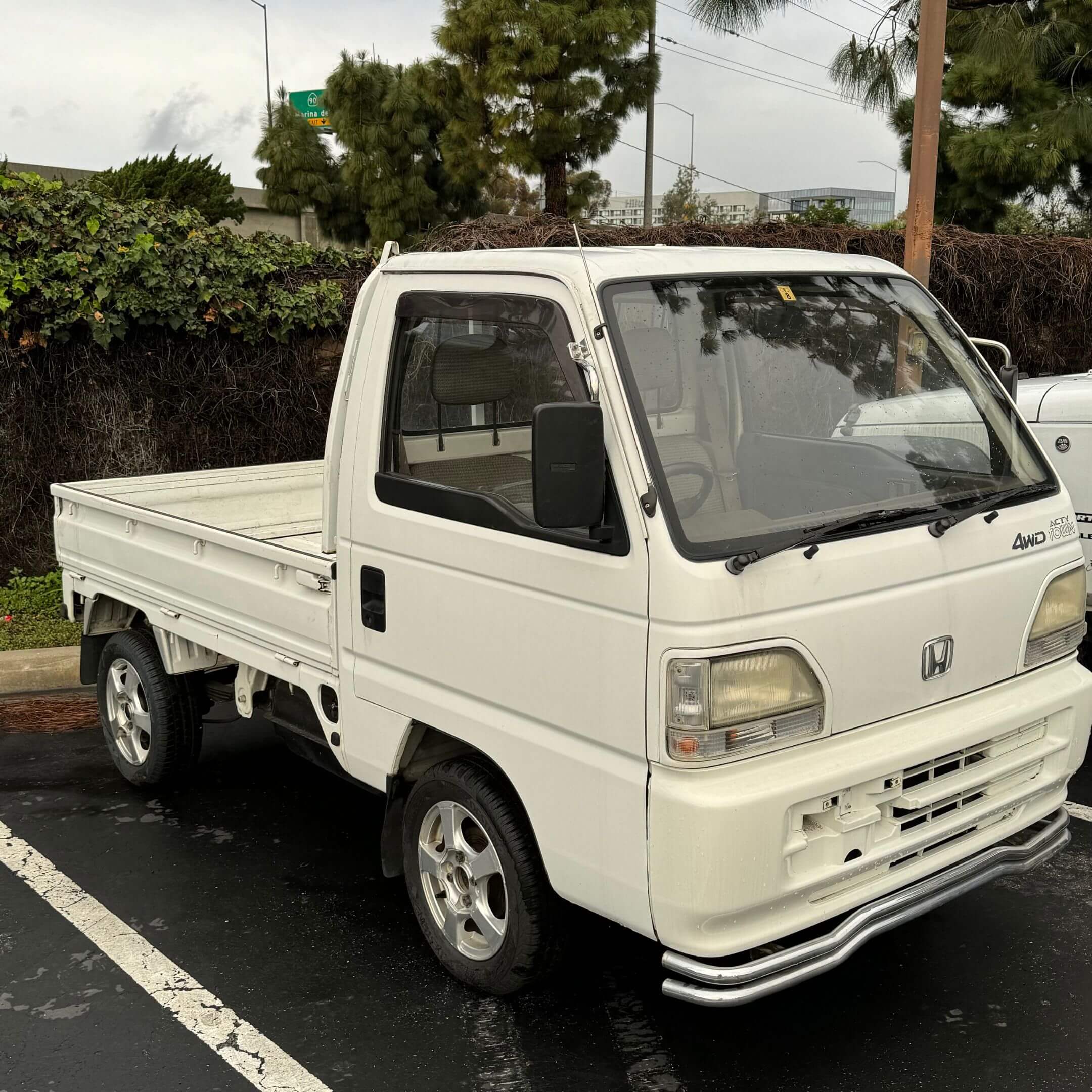 White 1994 Honda Acty Town Kei Truck with 4WD, AC, and 5-speed manual parked outdoors, showcasing front bumper and driver's side in clean condition.