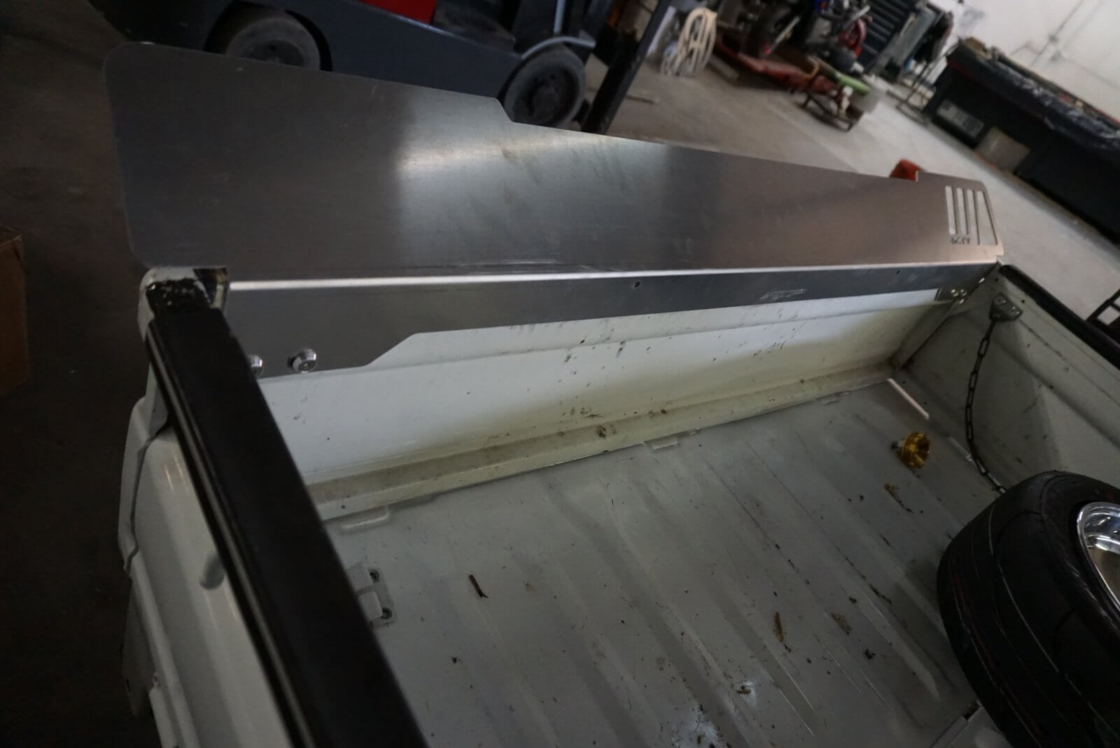 Rear Lusso Spoiler for Honda Acty Truck, silver aluminum, mounted on truck bed, industrial garage background