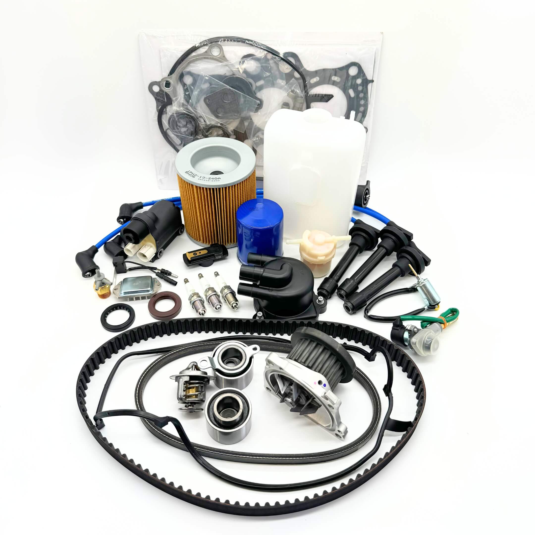 Complete 24-piece Mega Timing Belt and Tune Up Kit for 1990-1999 Honda Acty HH3/HH4, featuring OEM-quality air filter, fuel filter, oil filter, distributor cap and rotor, high-efficiency spark plugs with wires, ignition control module with coil sensor, ignition assembly, engine gasket set, timing and alternator belts, coolant reserve tank, air thermal valve, all displayed on a white background, exclusively available at Oiwa Garage with free shipping.