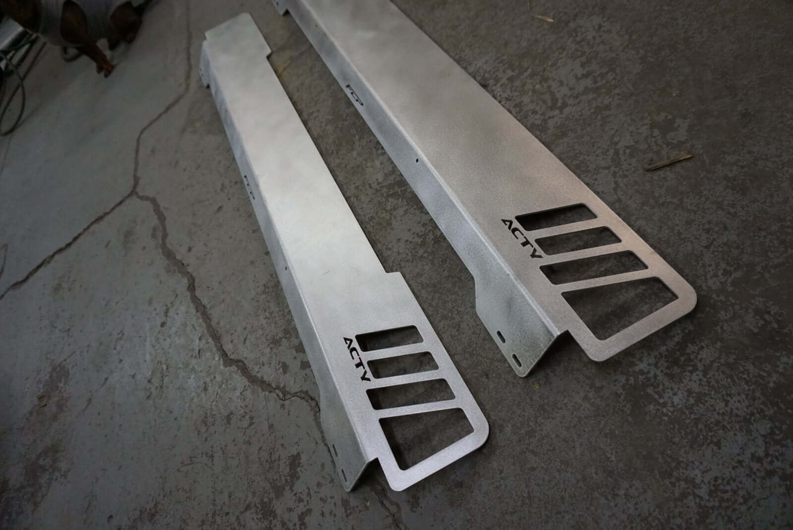 Rear Lusso Spoiler for Honda Acty Truck, silver aluminum, sleek design, angled cuts, laid on a textured gray surface