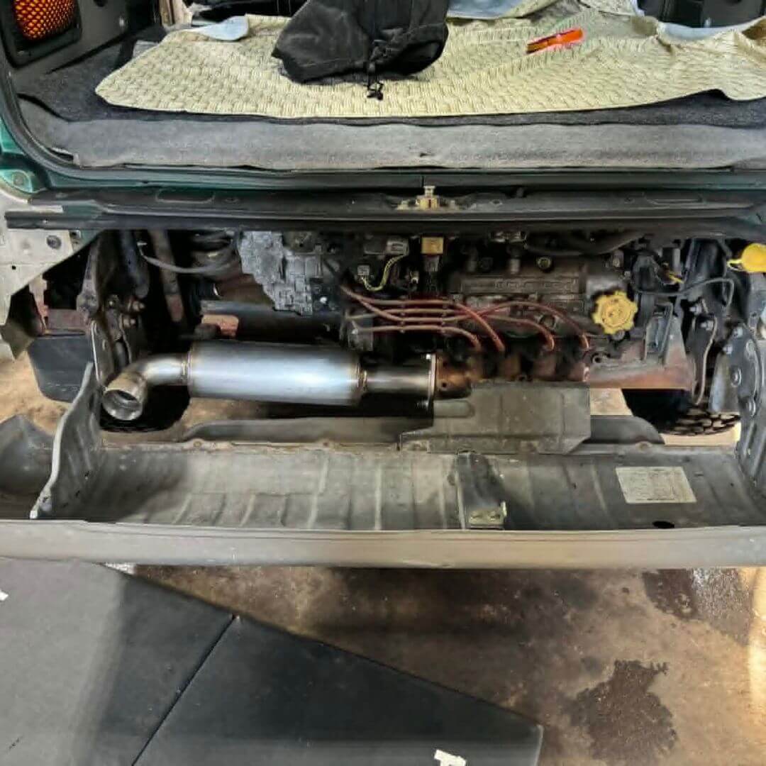 Oiwa Growler Exhaust installed behind the bumper of a Subaru Sambar Van TV1, TV2 model, showcasing a sleek and compact design for 1999-2012 vehicles.