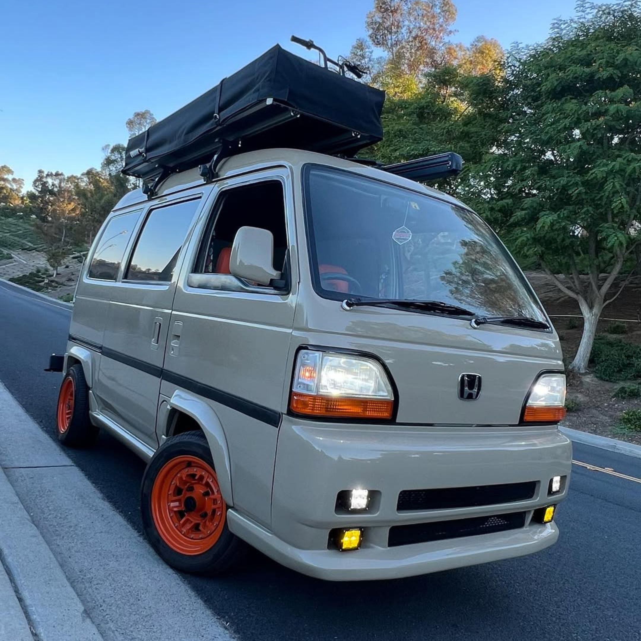 Tan Honda Acty Van HH3/HH4 (1992–1999) outfitted with Mag Factory Gloss White Fender Flares, showing the precise contour fit over bright orange wheels and a black roof rack for a rugged, customized mini‑van look.