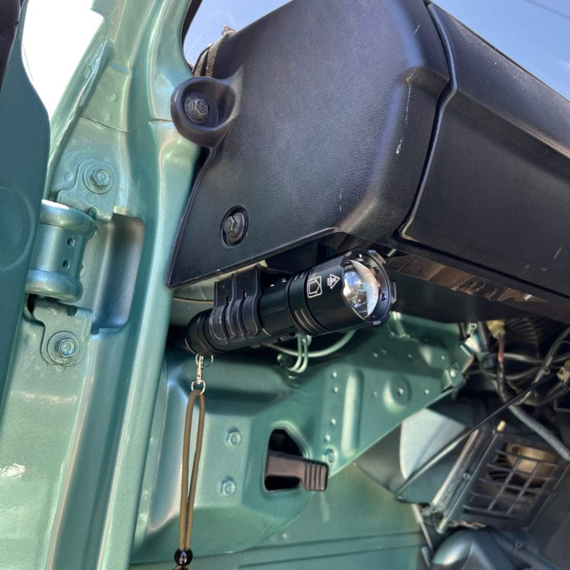 Oiwa UltraBeam 300W USB LED Flashlight mounted in a kei truck’s flare holder under the driver‑side dash for hands‑free tactical lighting.