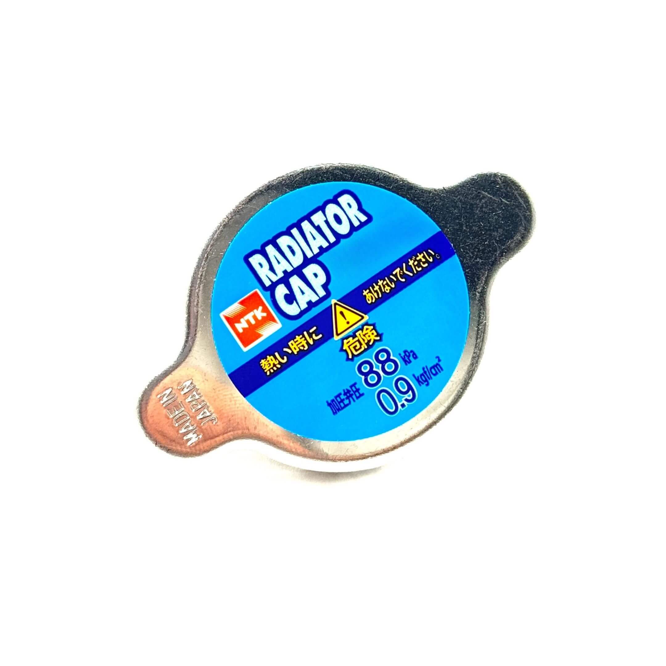 Aftermarket radiator cap for Subaru Sambar Truck TT1, TT2 models (1999-2012) with blue label, 0.9 kg/cm² pressure rating, and NTK branding.