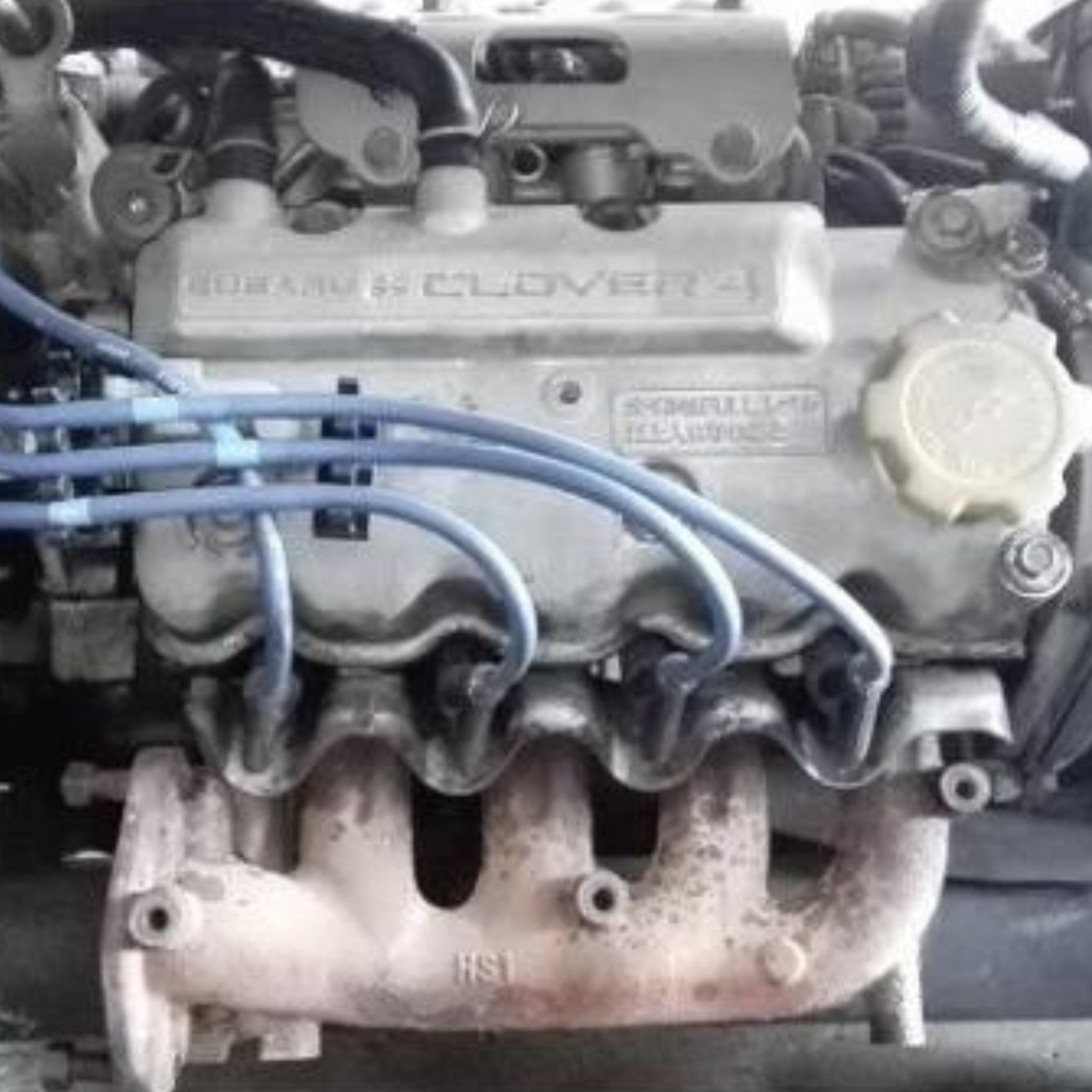 Subaru Sambar Van TV1, TV2 (1999-2012) Detailed engine view, featuring Clover 4 valve cover, ignition wires, and exhaust manifold components. – Engine Parts collection.