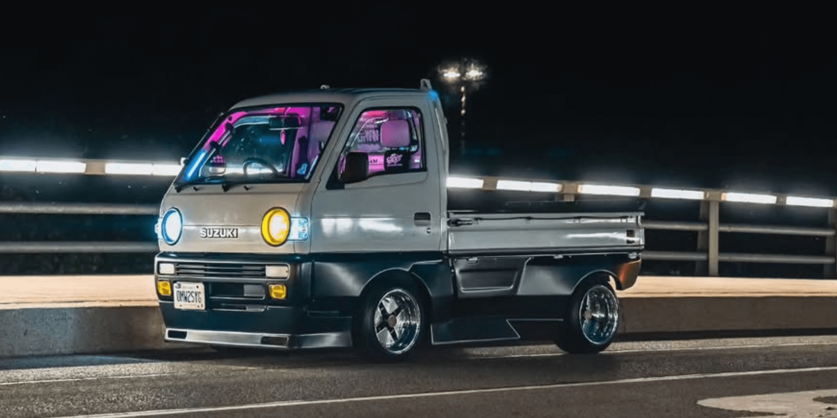 Customized Suzuki Carry Kei Truck DC51T, DD51T (1991-1998) with LED headlights, lowered stance, aftermarket wheels, and vibrant neon lighting upgrades.