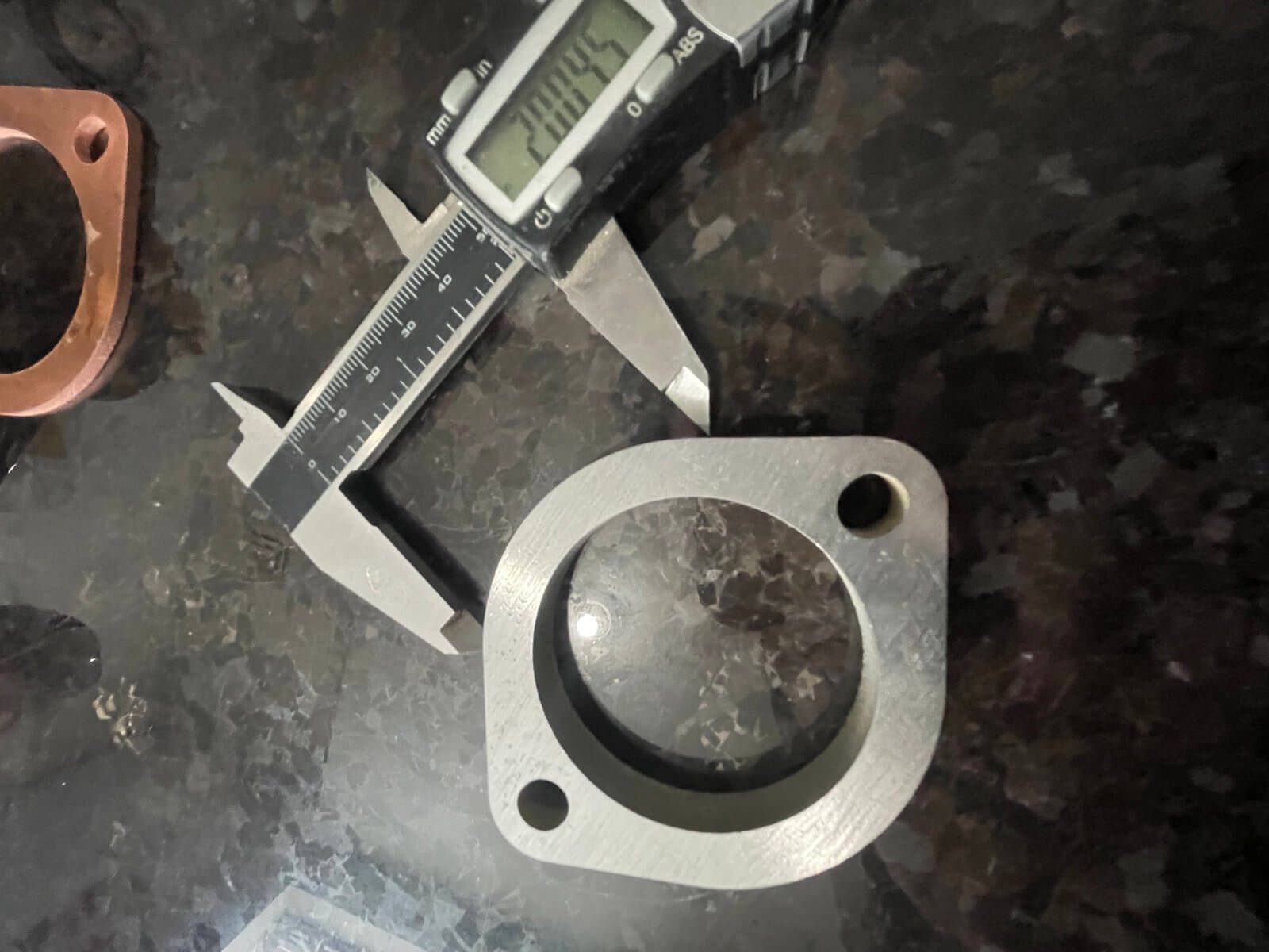 Precision-cut Honda Acty truck exhaust flange with caliper measuring 2 inches in diameter, designed for easy 1990-1999 model compatibility.
