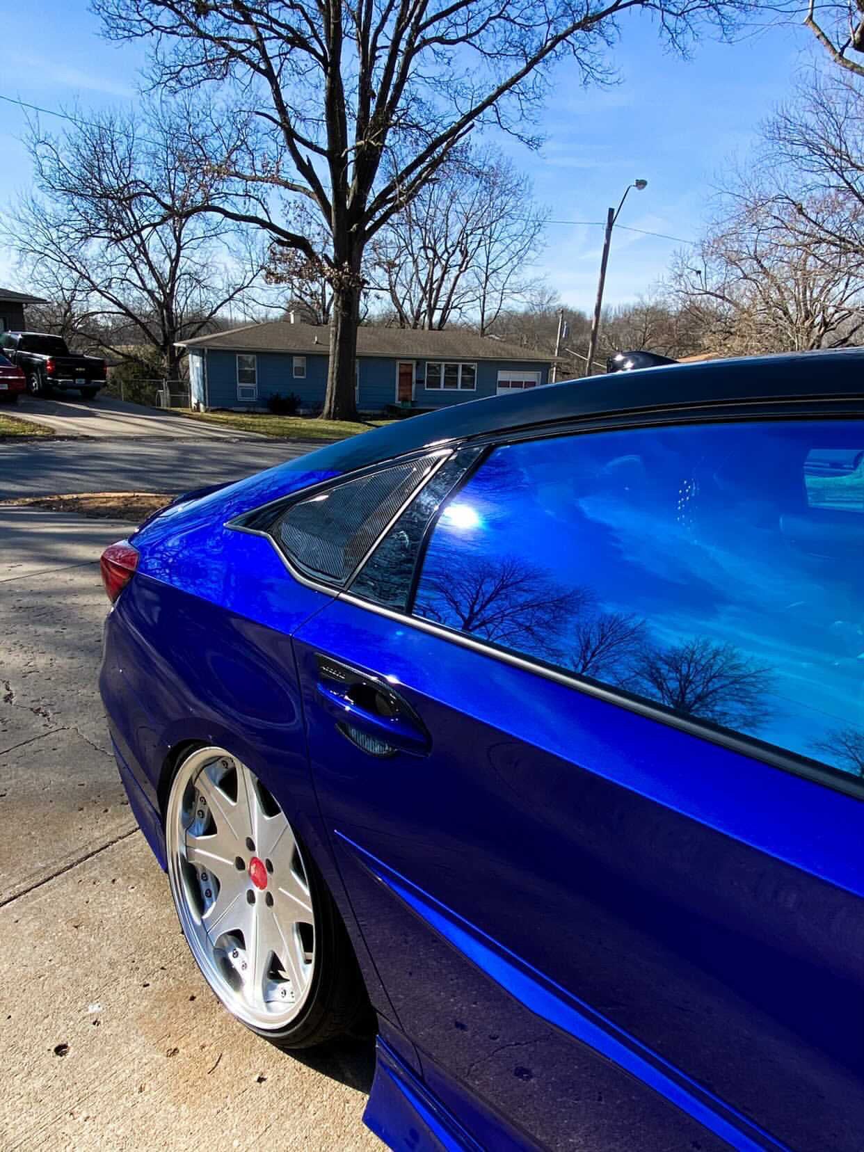 Close-up of Omnique Zircon Tint applied to a blue sedan, demonstrating its ceramic blue-tint technology.