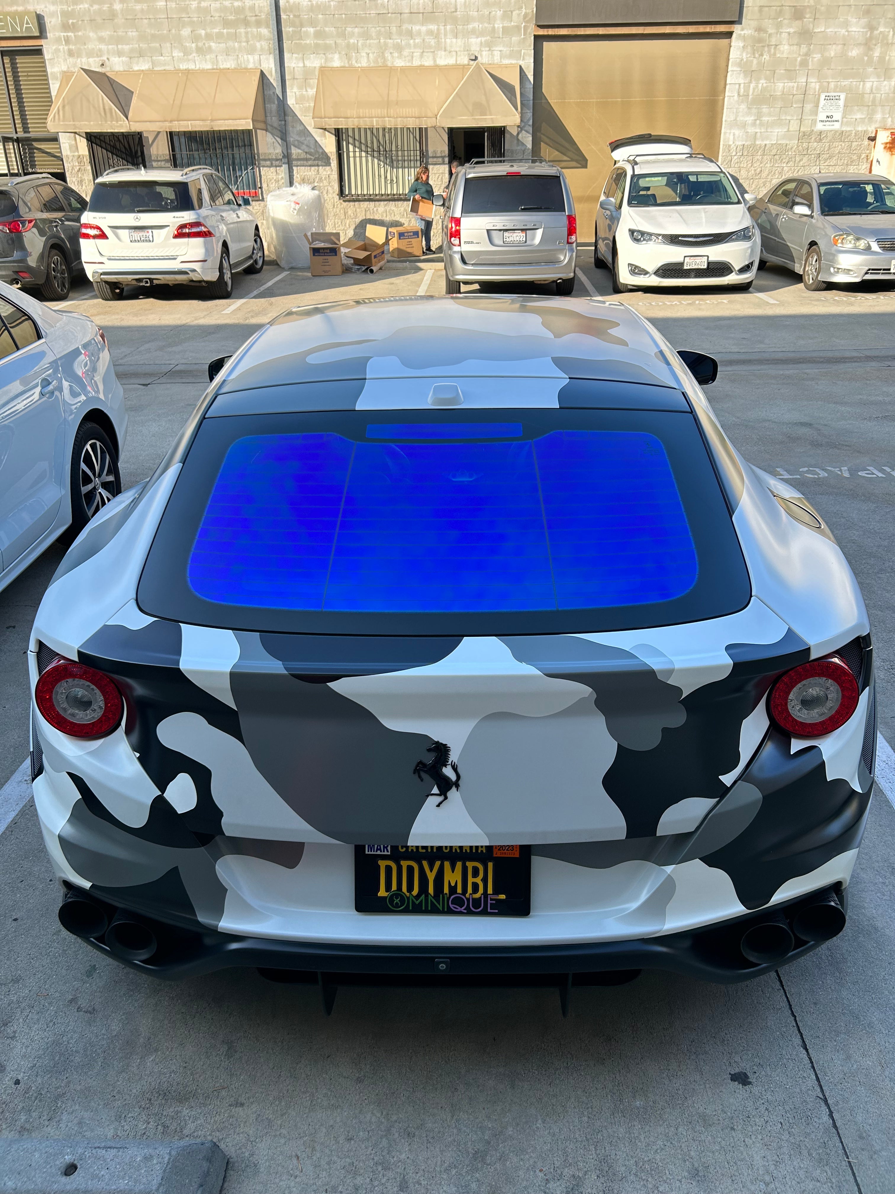 Camouflaged sports car with a bold blue Omnique Zircon Tint, showcasing the rear windshield.