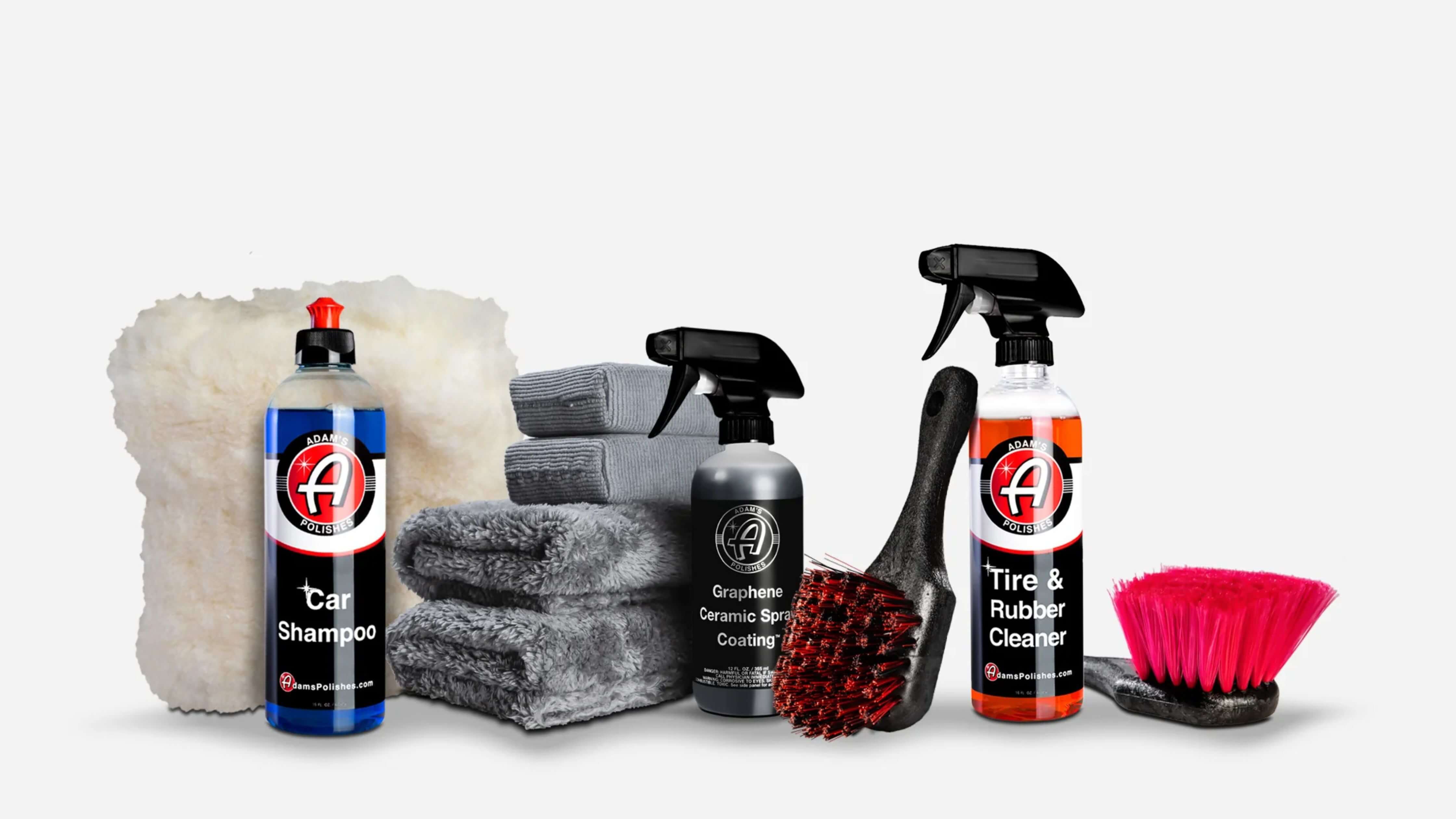 A collection of car cleaning products including car shampoo, graphene ceramic spray coating, tire and rubber cleaner, microfiber towels, and brushes.