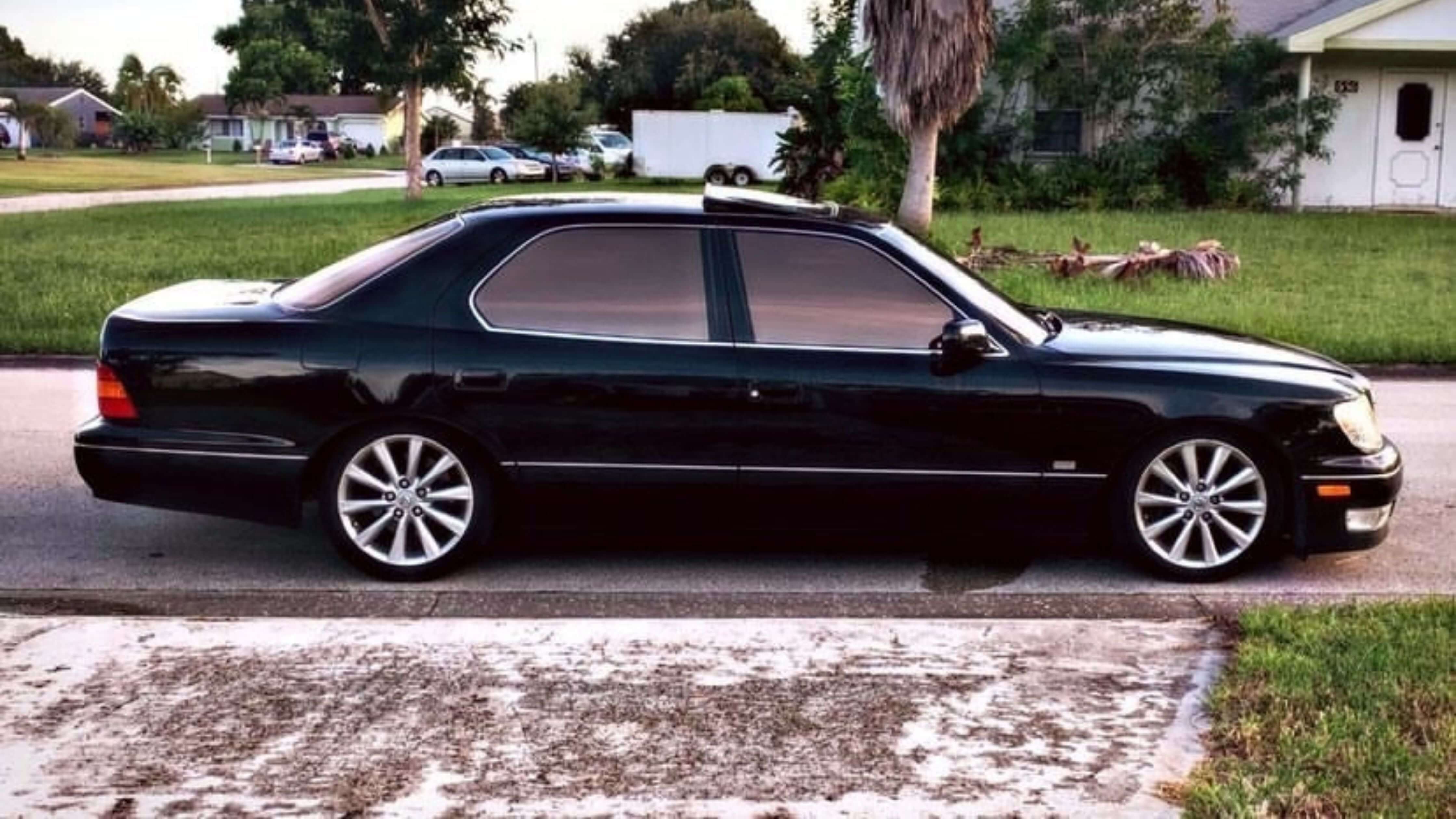 Car window tint pricing guide: black sedan with residential backdrop.