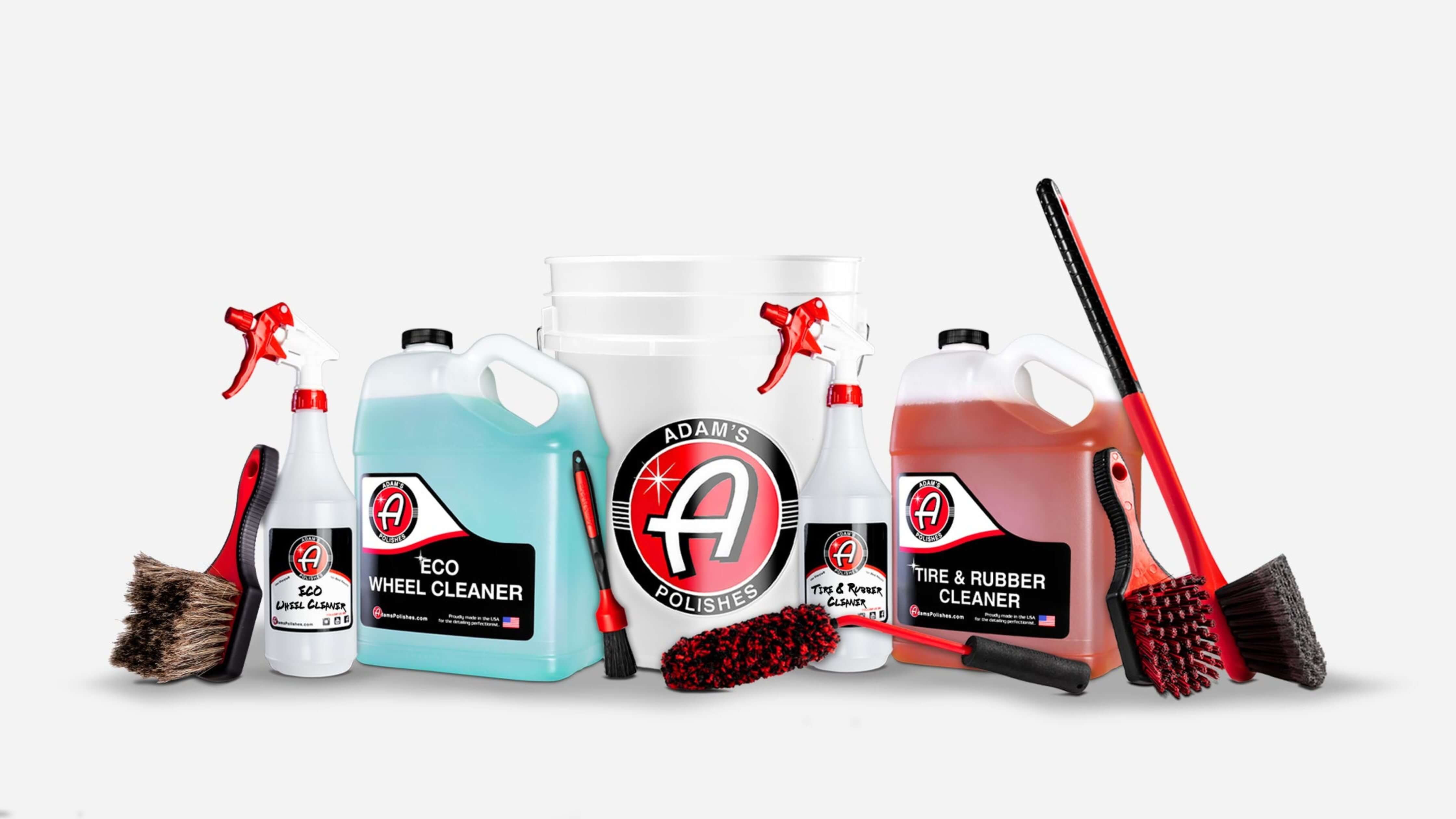 A collection of car cleaning products from Adam's Polishes, including bottles of cleaners, brushes, and a bucket.