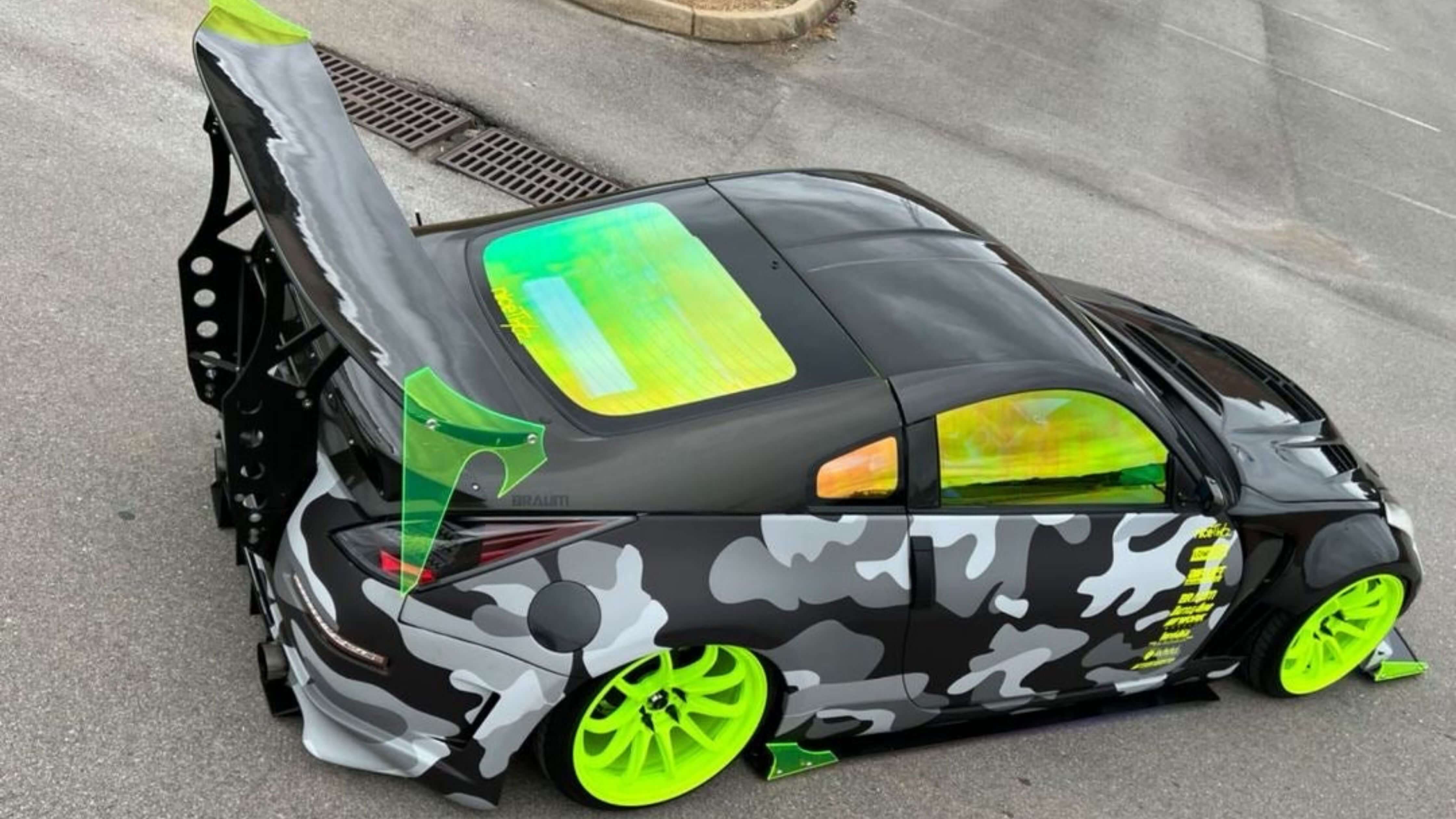 Stylish car with camouflage design, neon green wheels, and tinted windows.