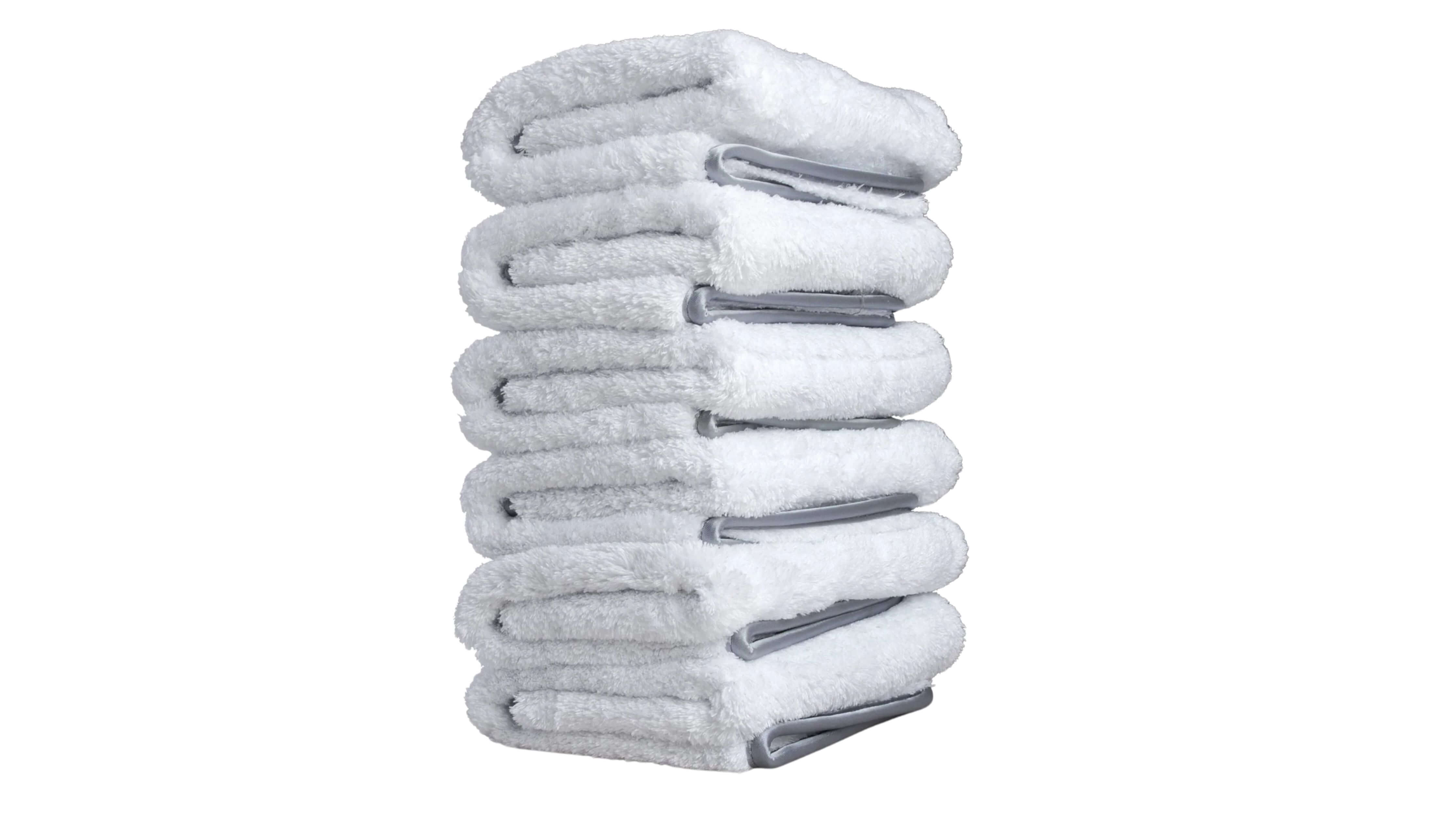 A stack of six neatly folded white microfiber towels with gray trim.