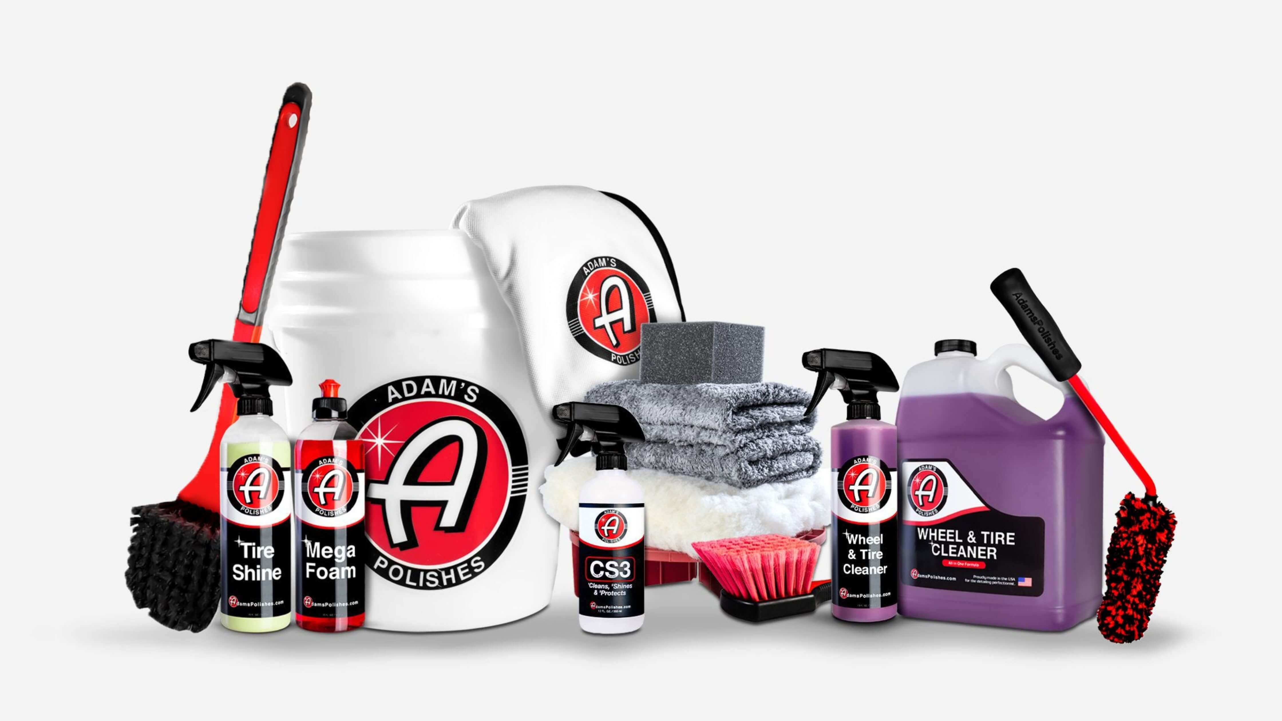 A collection of Adam's Polishes car cleaning products including bottles, bucket, towels, brushes, sponge.