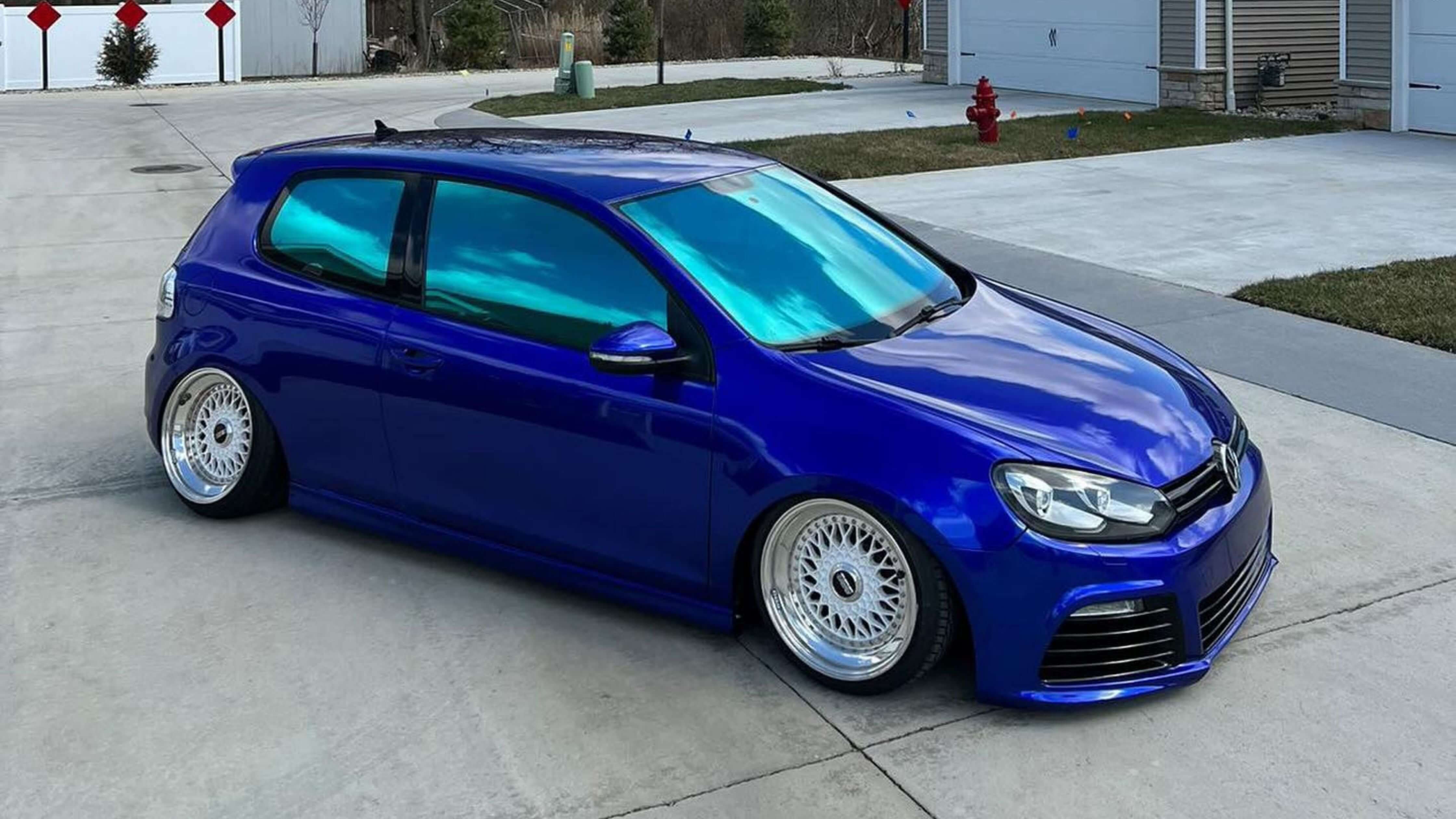 Blue hatchback car with tinted windows parked on a sunny street, emphasizing cooler interiors through effective window tinting.