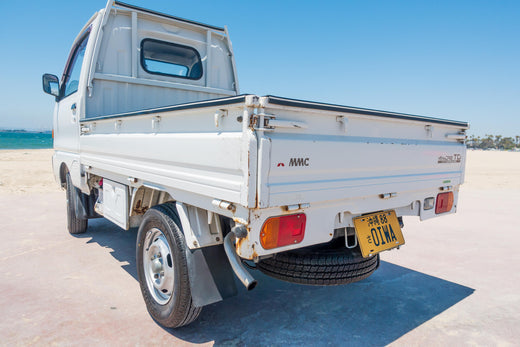 Rear View of a White Kei Truck Parked on the Beach with Ocean in the Background