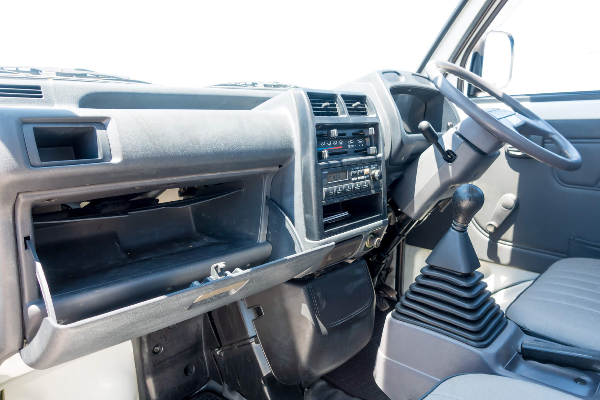 Interior of a Honda Acty showing dashboard, steering wheel, and gear shift lever.