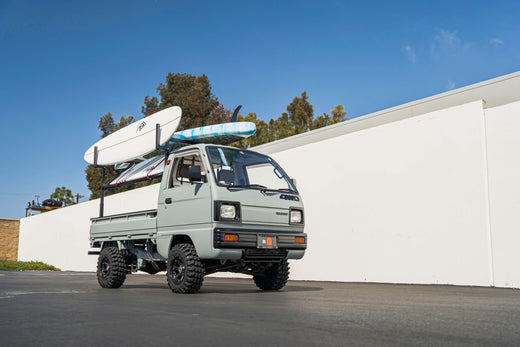 Lifted Kei Truck with Surfboards on Rack, Parked Outside on a Sunny Day