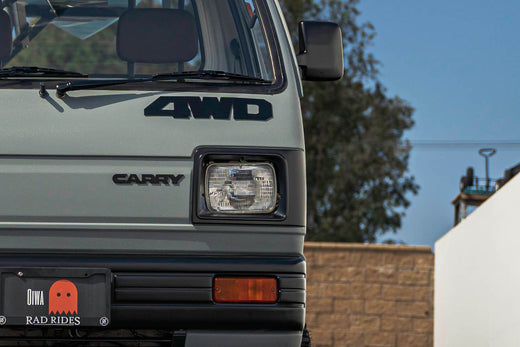 Close-up of a Suzuki Carry 4WD Kei Truck front grille and headlight on a sunny day