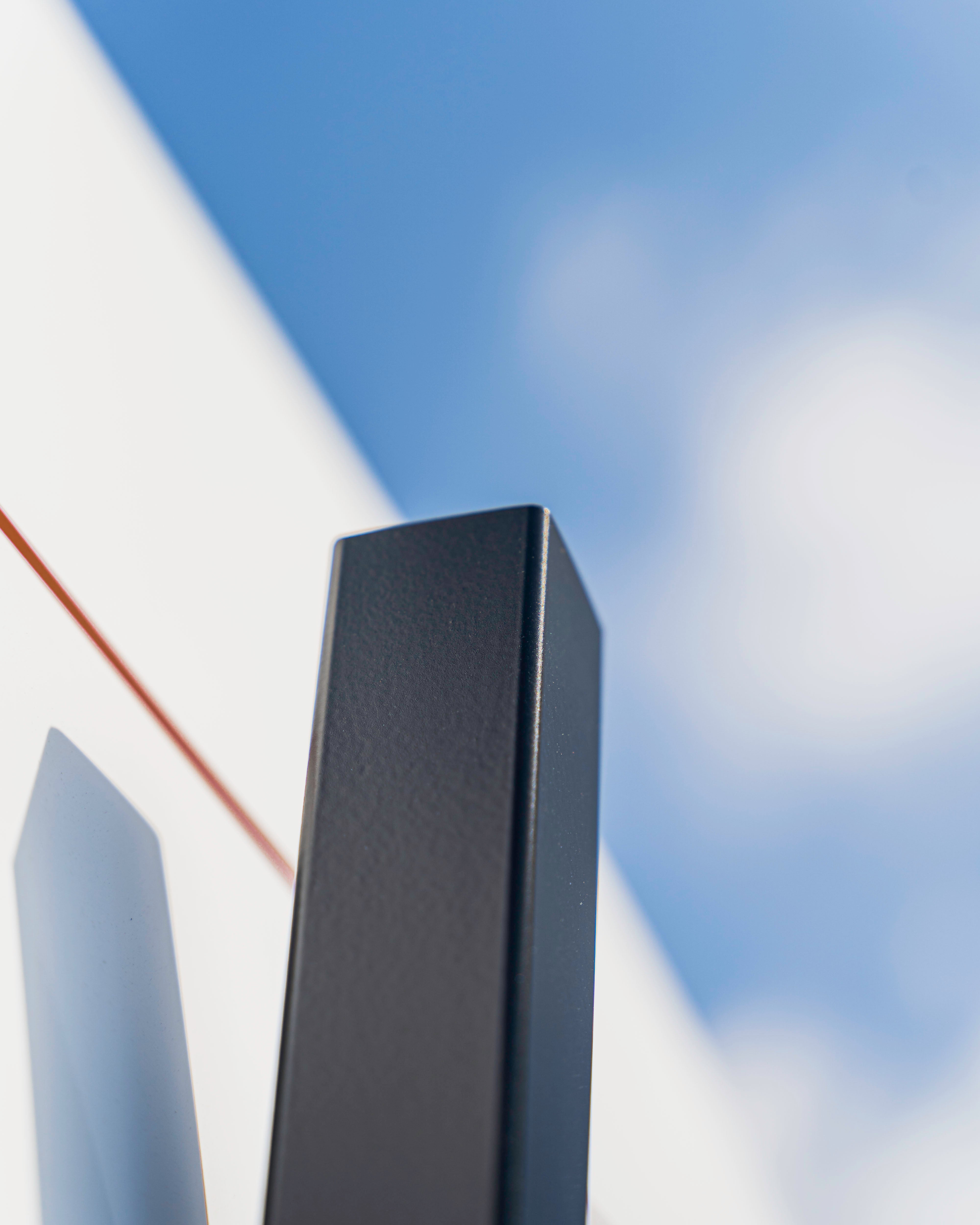 A close-up of a black rectangular object against a blue sky with a white structure in the background.