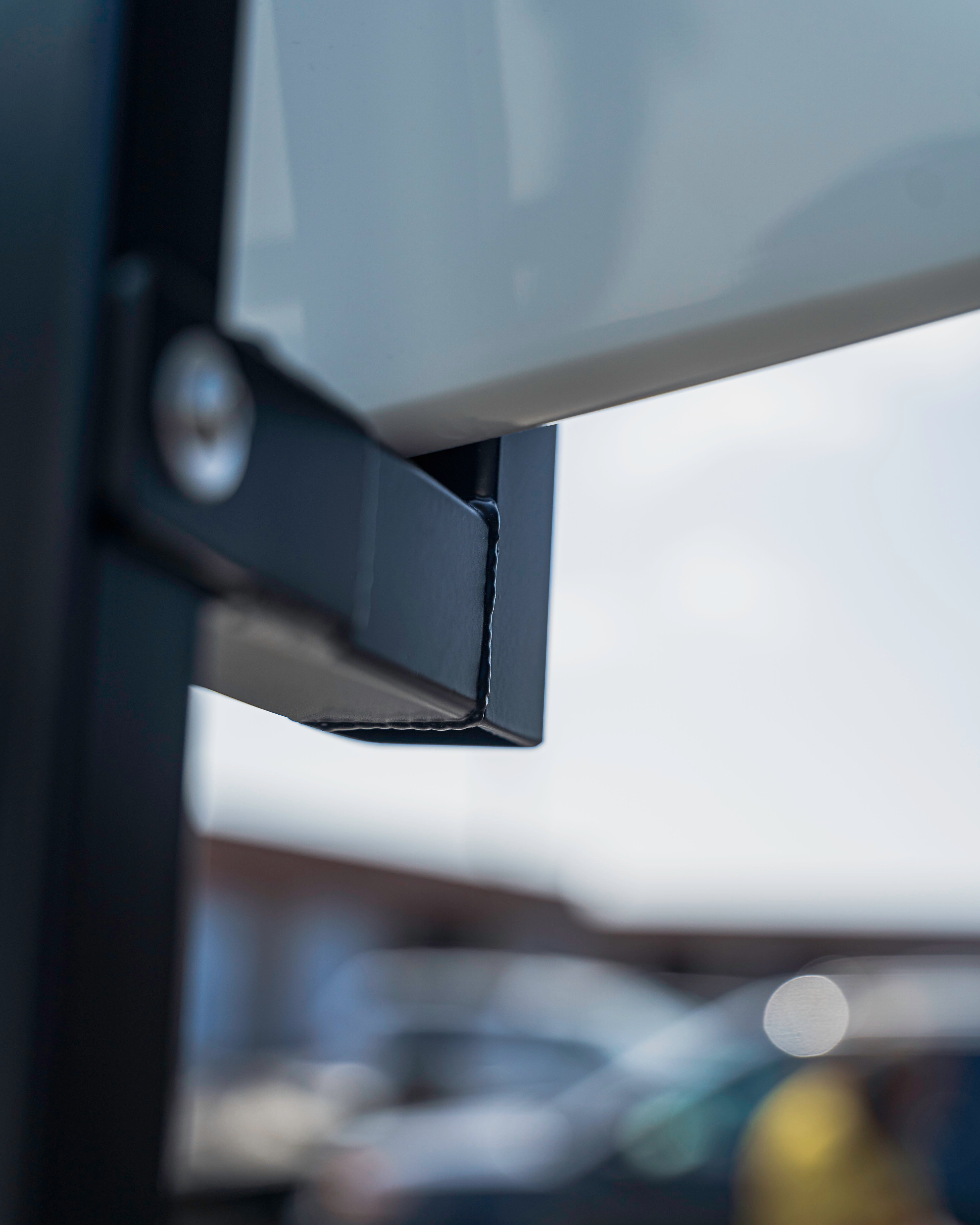 Close-up of a metal bracket attached to a white surface, with a blurred background.