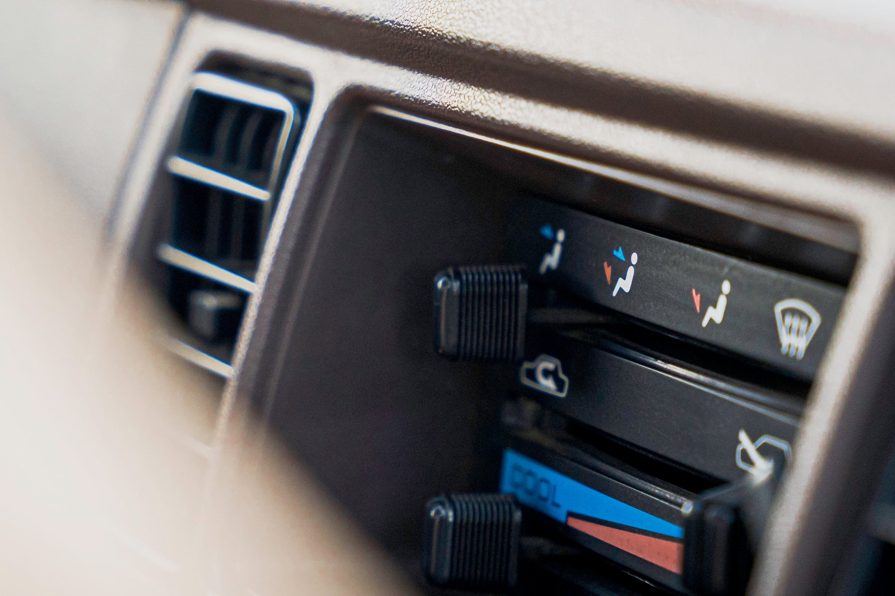 Close-up of a car's climate control panel with air vent and temperature adjustment sliders.