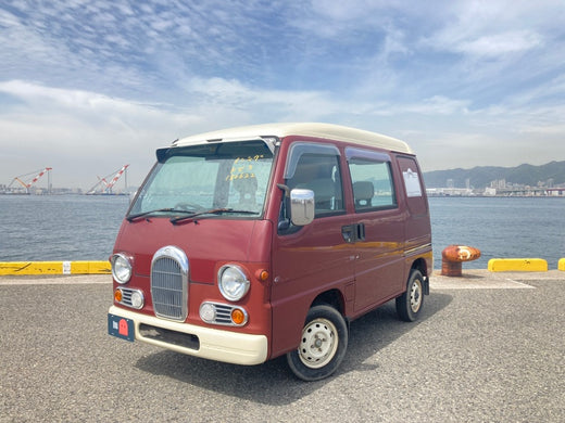 Red and White Subaru Sambar Dias Parked by the Waterfront with Industrial Background