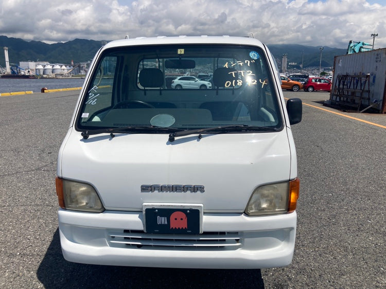 Front view of a white Subaru Sambar Kei truck with Oiwa Garage license plate, showcasing its compact design and practicality for Ohio buyers. Ideal for import enthusiasts seeking 'Subaru Sambar for Sale Ohio' options.