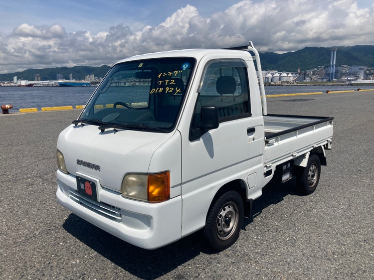 Front-side view of a white Subaru Sambar TT2 Kei truck, showcased with a coastal backdrop, perfect for California's utility and style needs. Discover more at OiwaGarage.co.