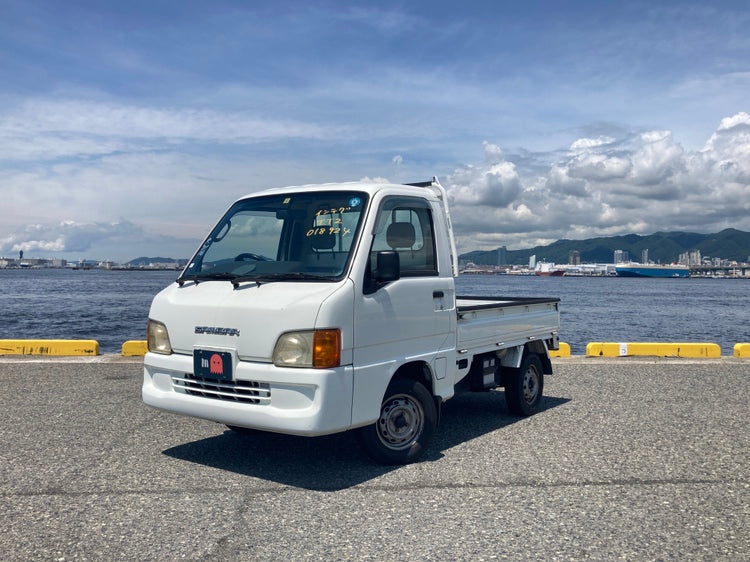 Subaru Sambar for Sale in Texas - Compact Kei Truck with scenic waterfront backdrop, highlighting its versatile design and practicality for Texan lifestyles.