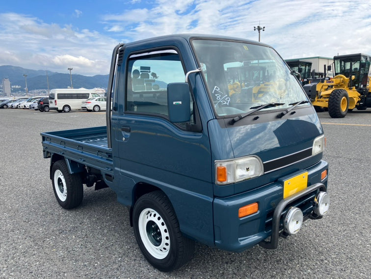 Lifted Subaru Sambar parked with construction equipment, symbolizing adventure.