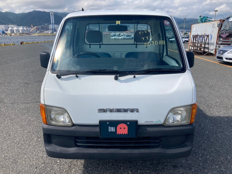 Front view of a white Subaru Sambar kei truck with Oiwa license plate, showcasing its compact design and classic styling. Import your Sambar with Oiwa.co today.